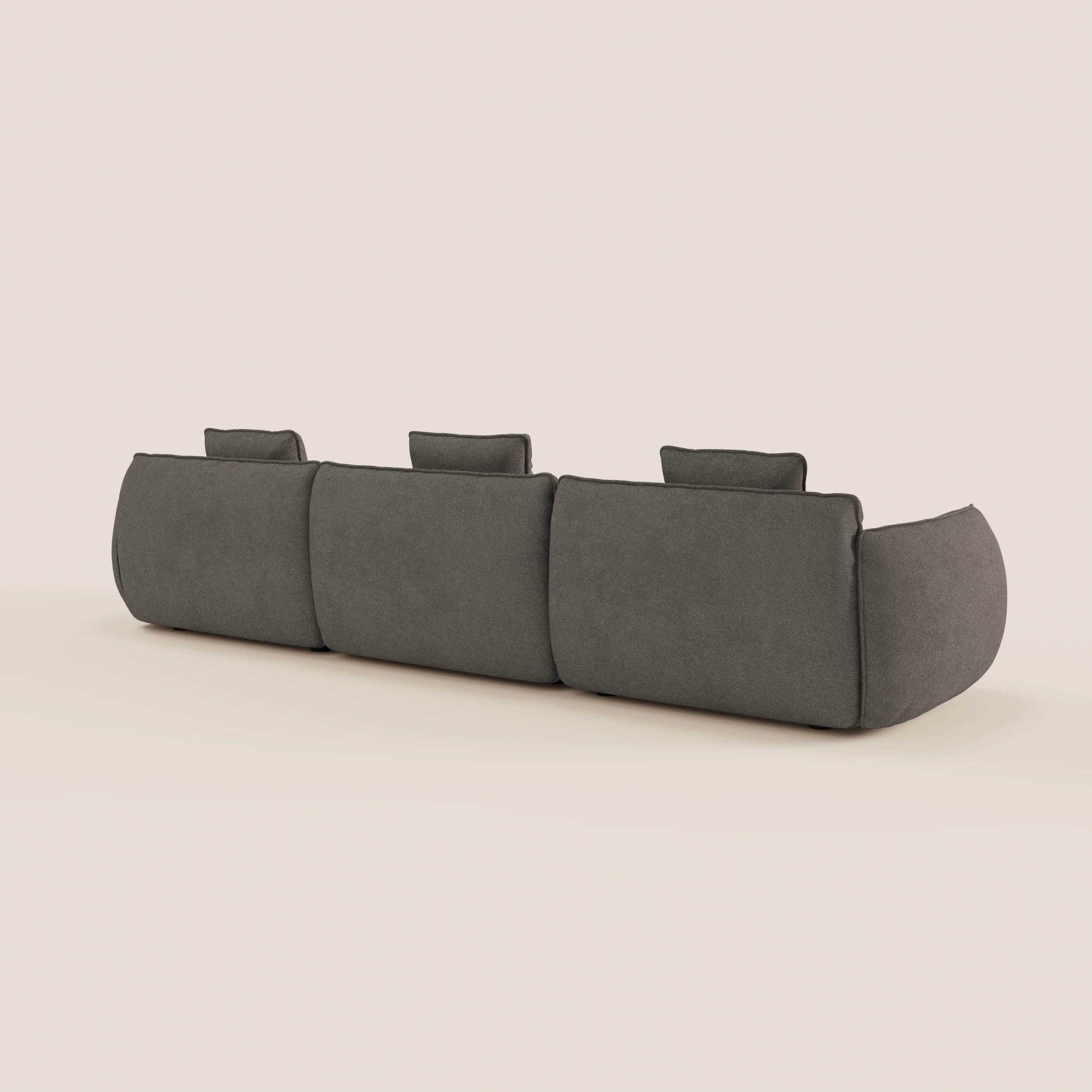 Il Nimbus divano modulare a 3 sedute di Divani.Store in tessuto smacchiabile T33 grigio scuro è mostrato da dietro, con tre poggiatesta e braccioli arrotondati, su uno sfondo beige chiaro.