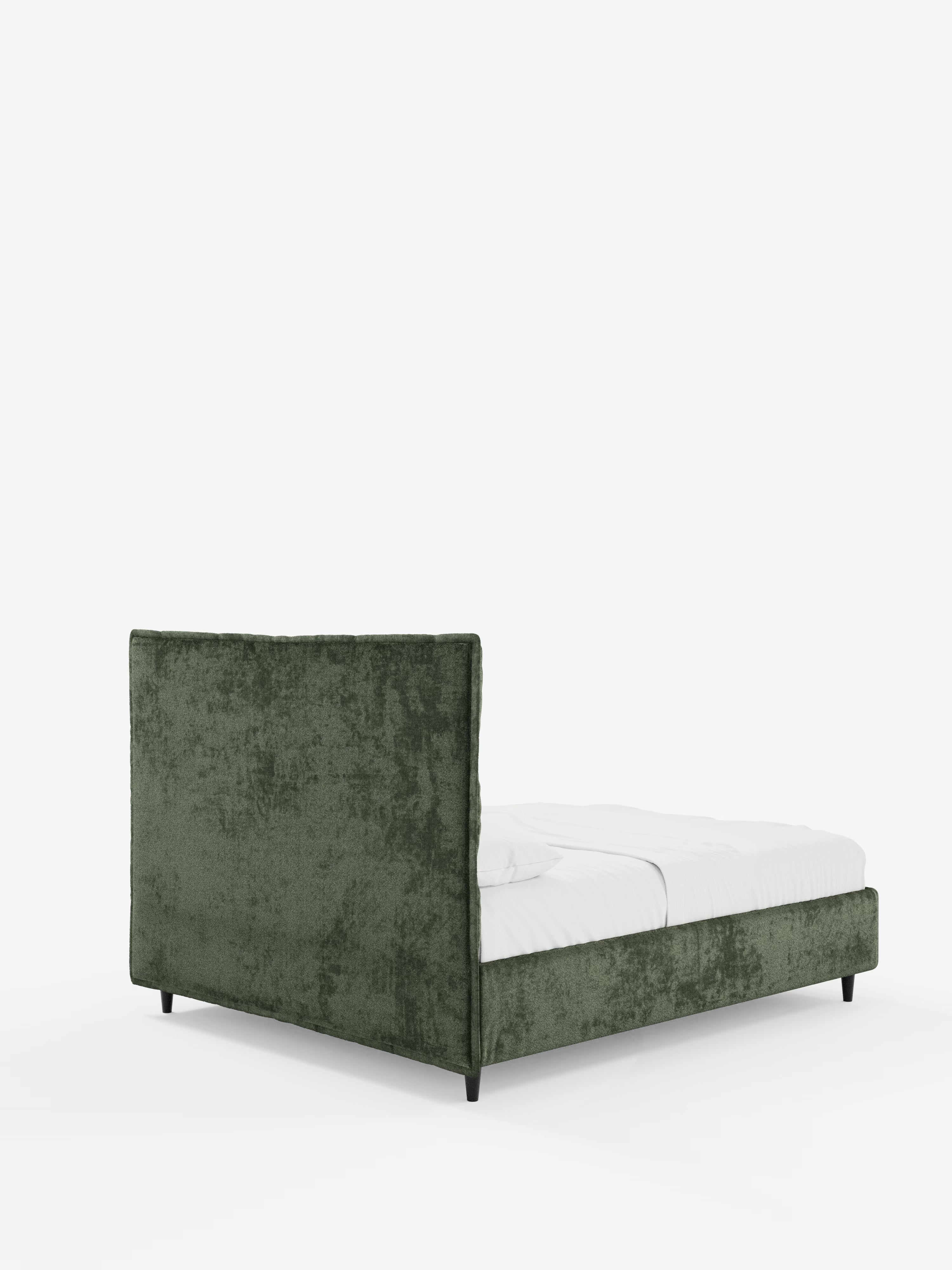 Il letto imbottito AURO di Letti.store è un letto in stile contemporaneo con rivestimento in ciniglia (chenille) di colore verde certificato Oeko-Tex®, caratterizzato da un'alta testiera capitonné trapuntata, un ampio vano contenitore, biancheria da letto bianca e gambe nere, il tutto su uno sfondo bianco.