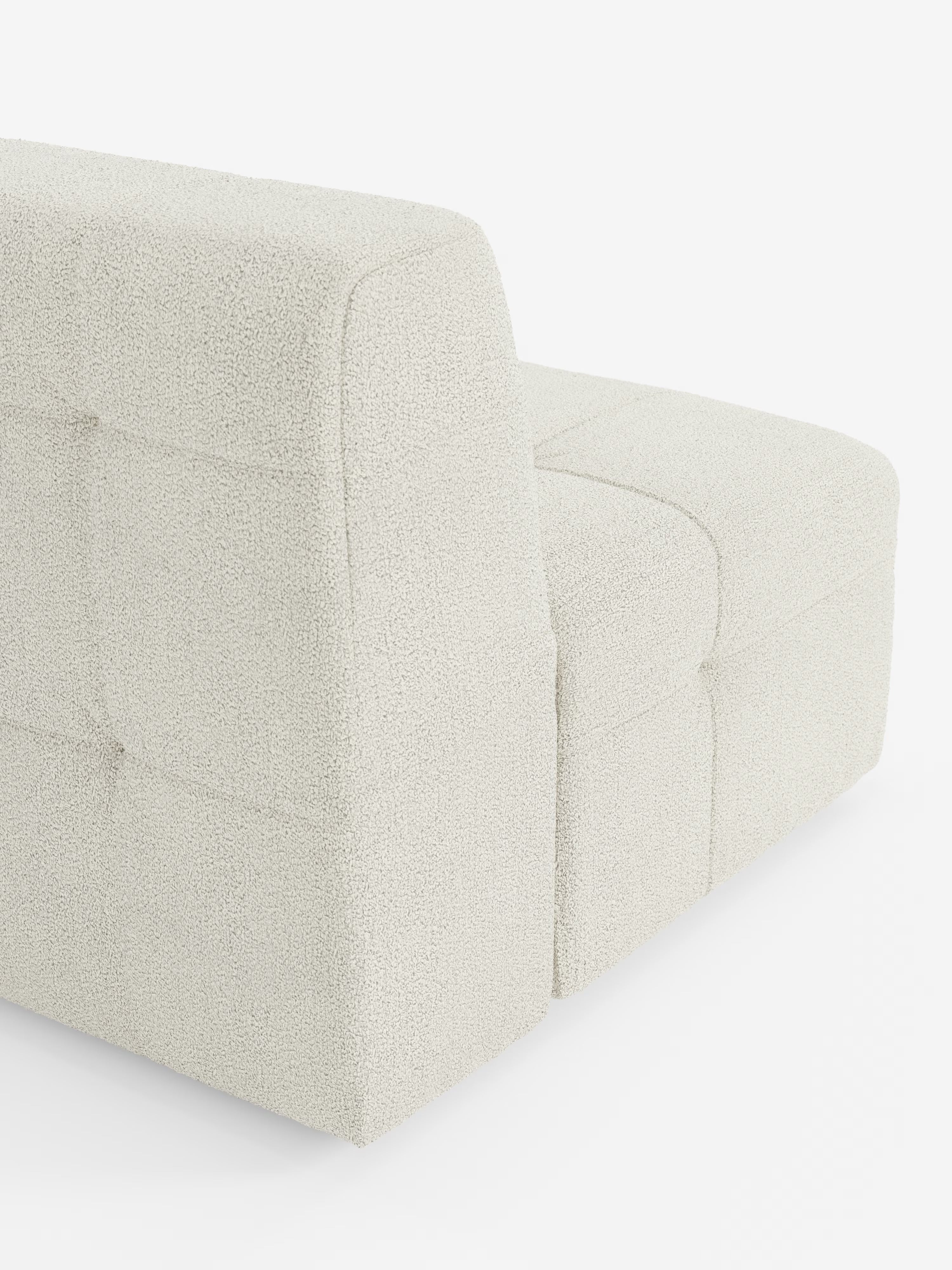 Un primo piano della poltrona Mosaic modulo da 77 cm in bouclé - capitonné e design in tessuto antimacchia T21 di Divani.Store, un moderno divano senza braccioli rivestito in tessuto bouclé bianco sporco, testurizzato e antimacchia. Il design raffinato presenta morbide sezioni trapuntate a quadrati e linee pulite che esaltano l’essenza dello stile classico della poltrona. Su uno sfondo completamente bianco, l’immagine mette in risalto il colore chiaro e la morbida trama di questo elegante divano.