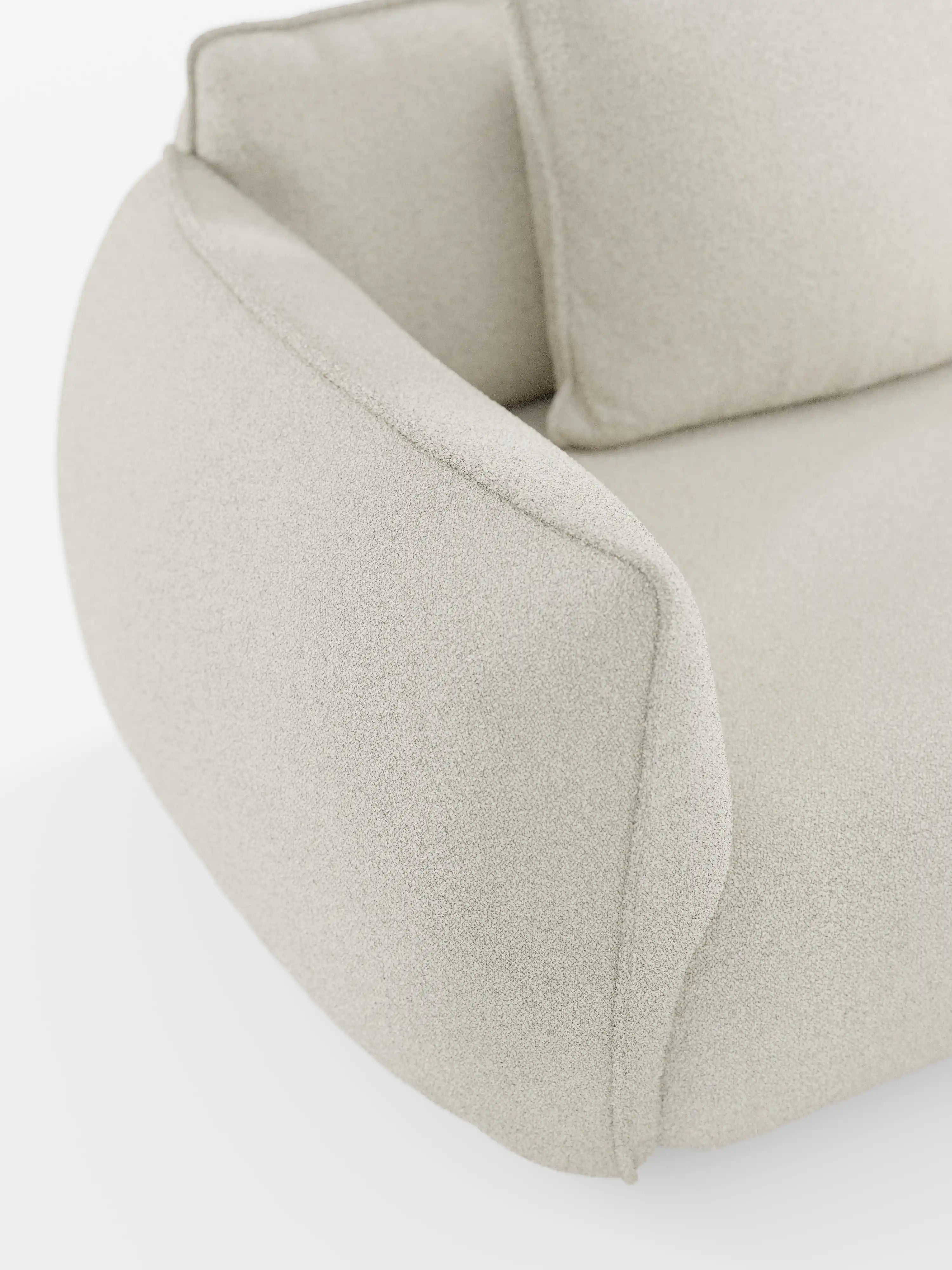 Primo piano del divano Nimbus a 3 posti, modulare e componibile, da 250 cm di Divani.Store, rivestito in tessuto smacchiabile effetto cotone (tessuto smacchiabile effetto cotone t33) di colore beige chiaro. Ispirata al design dei divani modulari, questa poltrona presenta un bracciolo ricurvo verso l’esterno e uno schienale morbido e imbottito. Il look complessivo è lussuoso e contemporaneo, caratterizzato da linee pulite e arrotondate.