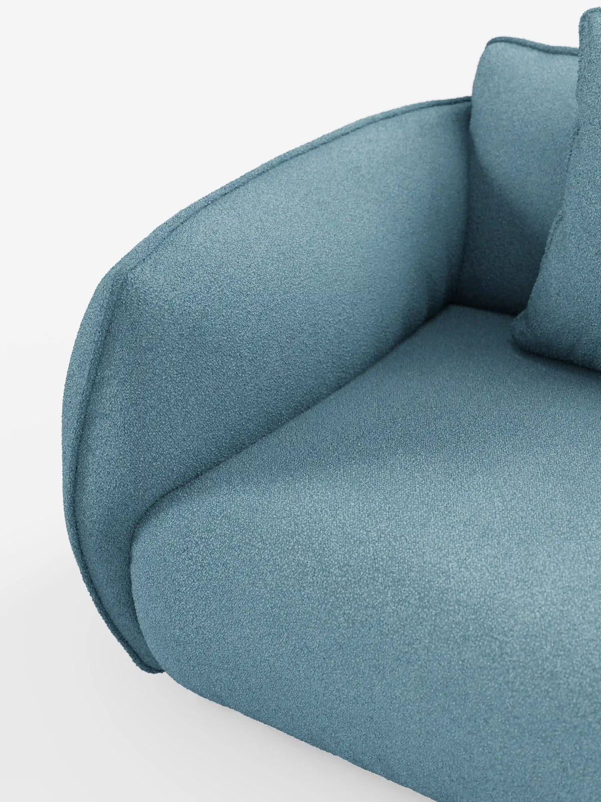 Un primo piano del divano angolare con penisola componibile Nimbus di Divani.Store, rivestito in morbido tessuto T33 blu con effetto cotone, resistente alle macchie. L'immagine mette in risalto il bracciolo, che si fonde armoniosamente con la seduta e lo schienale, con un cuscino blu coordinato parzialmente visibile su uno sfondo bianco.