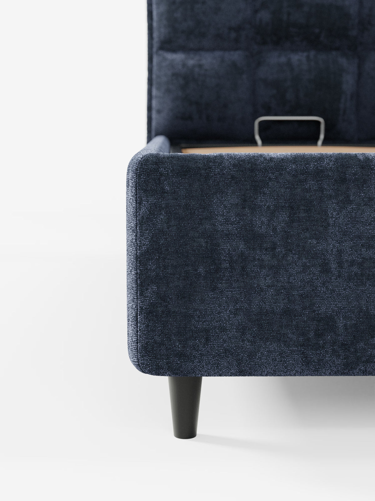 Primo piano del letto imbottito AURO con contenitore e testiera alta capitonné in ciniglia Oeko-Tex® di Letti.store in blu navy, che mette in risalto la sua elegante testiera alta con trapuntatura a quadrati. L'immagine mette in risalto il profilo laterale e la pediera di questa moderna struttura letto con gambe in legno scuro e design minimalista, su uno sfondo bianco a tinta unita.