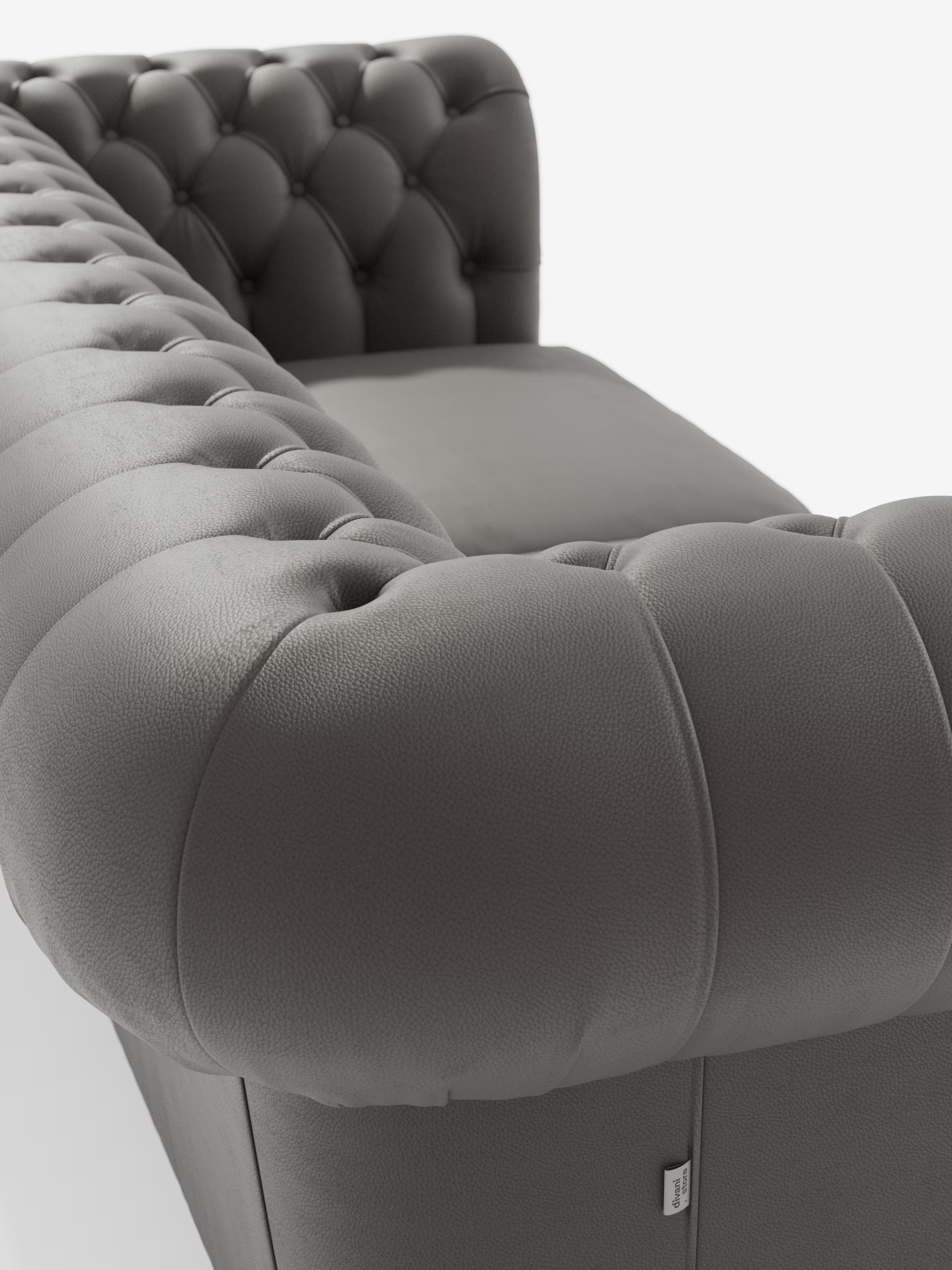 Primo piano del bracciolo e dello schienale di Chester, un divano in pelle grigia trapuntata caratterizzato da profondi bottoni decorativi. Questo Chesterfield di Divani.Store offre un'imbottitura morbida ed elegante e un'eleganza senza tempo come divano Chesterfield in vera pelle spessorata a 2 e 3 posti, realizzato artigianalmente in Italia e presentato su uno sfondo bianco a tinta unita.