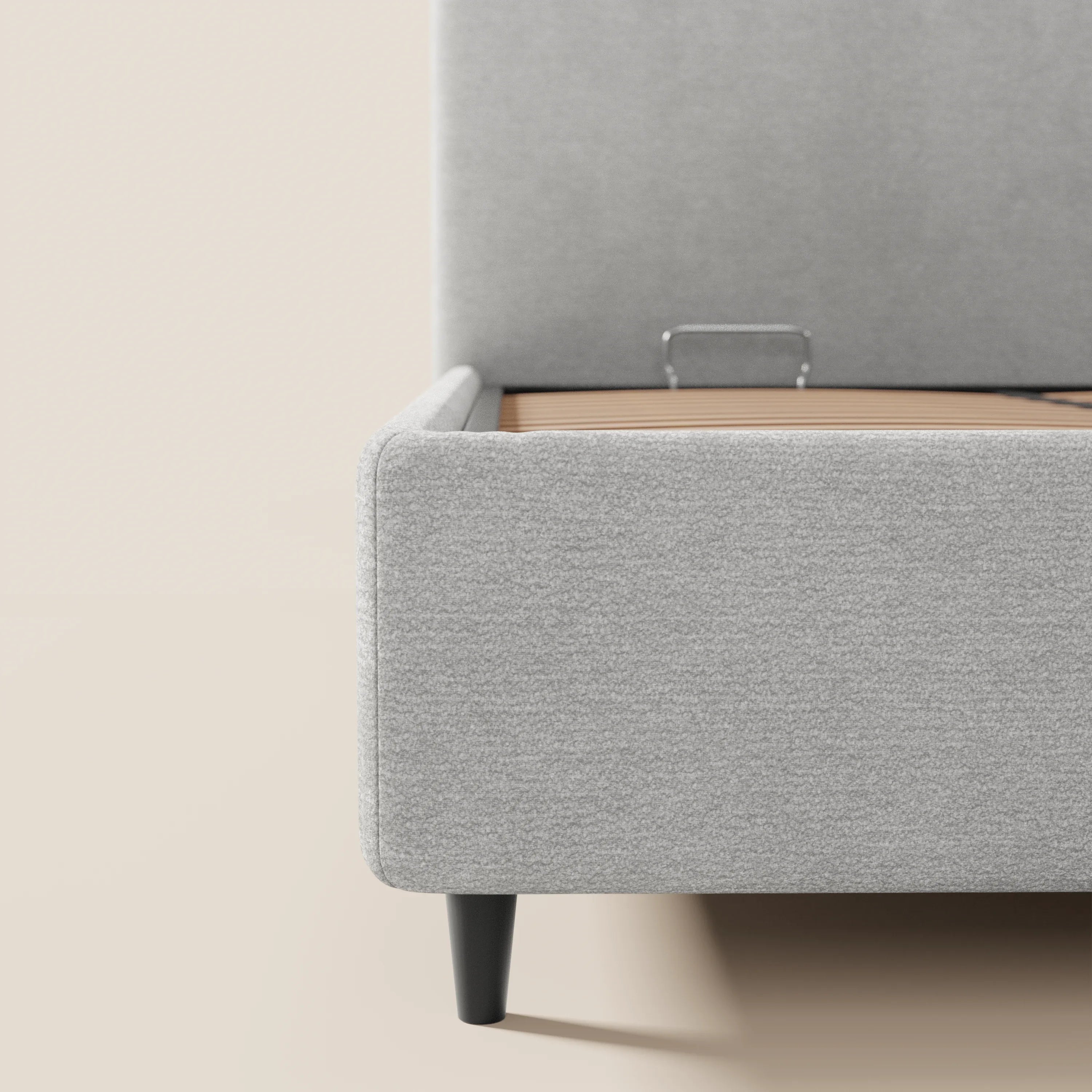 Un primo piano del letto imbottito KAELOS minimal di Letti.store ne mette in risalto il rivestimento in ciniglia grigio chiaro, le gambe alte nere e la testiera arrotondata, sottolineando le linee pulite e il design minimalista in una camera da letto dai toni neutri del beige.