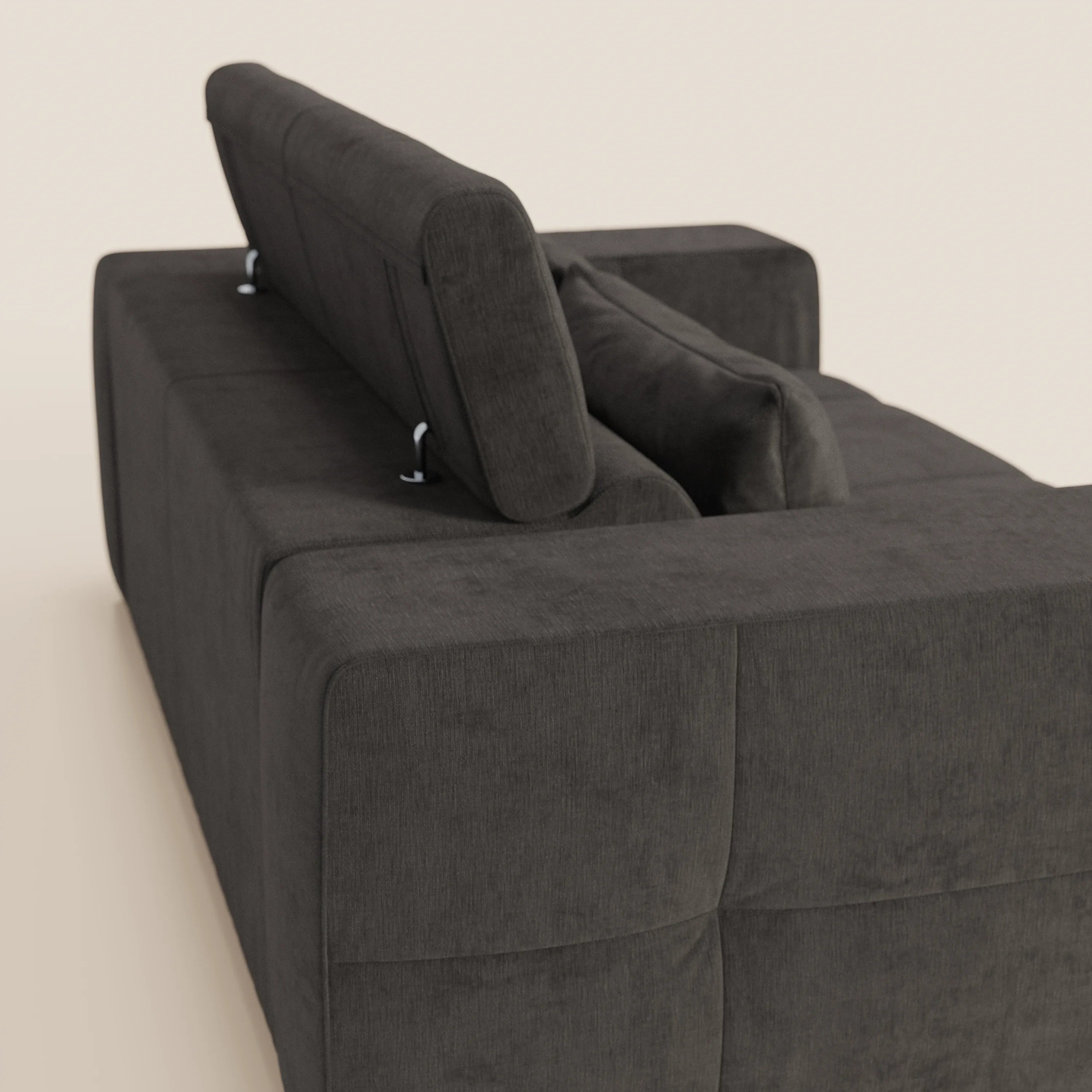 Il Monarch Divano con Relax Elettrico di Divani.Store è un moderno divano grigio scuro con braccioli imbottiti, poggiatesta regolabili, morbido tessuto antimacchia T31 e cuscino coordinato, visto dal retro su uno sfondo beige chiaro.