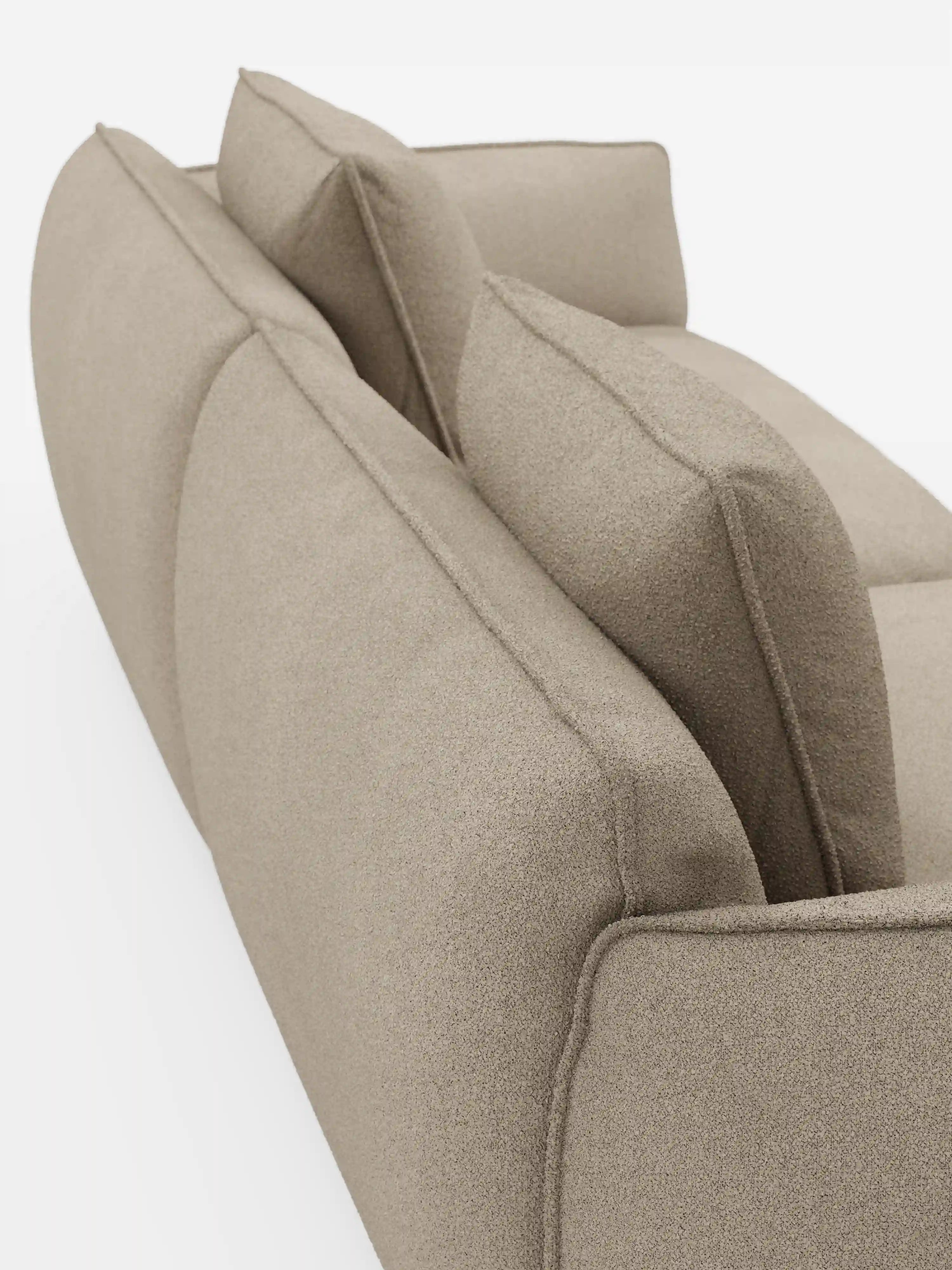 Una vista ravvicinata e obliqua del divano Nimbus a 3 posti, modulare e componibile, da 250 cm, di Divani.Modello sfoderabile in tessuto smacchiabile effetto cotone T33 in una moderna finitura beige, caratterizzato da braccioli e schienale curvi con due cuscini quadrati sulla seduta e due contro lo schienale. Lo sfondo è bianco a tinta unita.