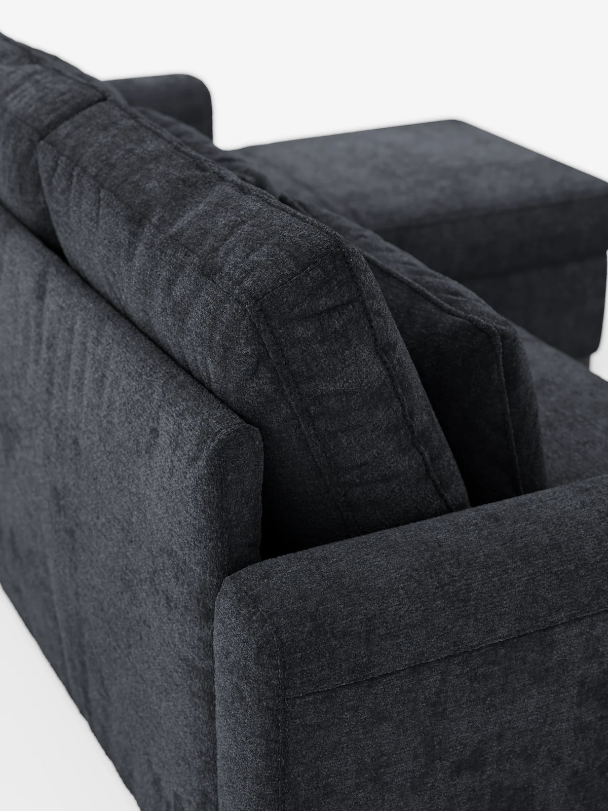 Un divano letto Ottaviano con chaise longue estraibile - penisola reversibile e contenitore in tessuto materico smacchiabile, grigio antracite, con chaise longue, tessuto materico, morbidi cuscini dello schienale e braccioli bassi e rettangolari su sfondo bianco.