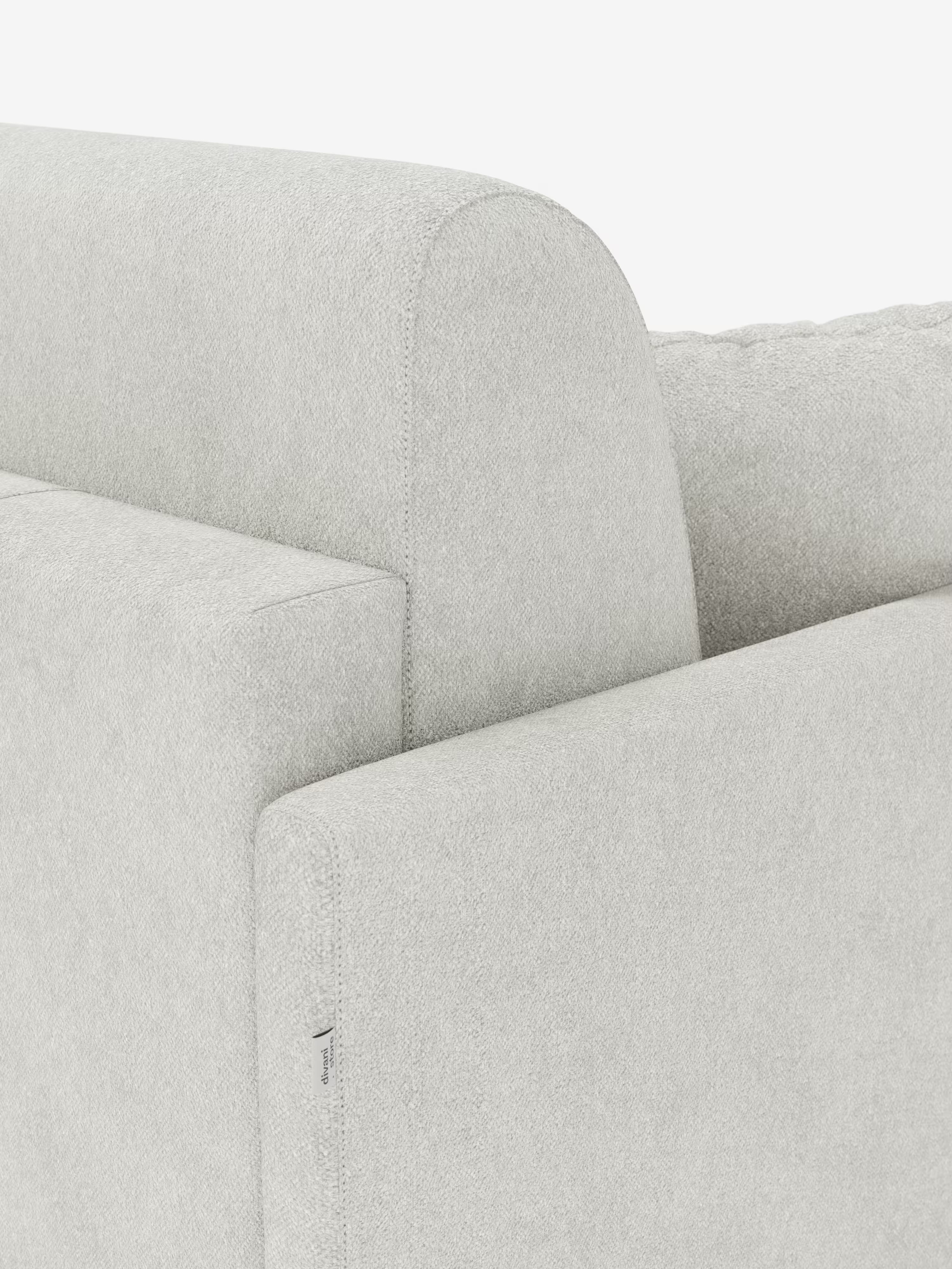 Primo piano del divano letto Tommy Divano a 2 e 3 posti matrimoniale di Divani.Store, nella versione grigio chiaro. L’attenzione è rivolta allo schienale liscio e ai braccioli sottili, che sottolineano l’elegante design del divano e il rivestimento facilmente sfoderabile in tessuto simile al cotone antimacchia (T33). Sulla cucitura interna del bracciolo è visibile una piccola etichetta in tessuto bianco con una scritta. Lo sfondo è bianco a tinta unita.