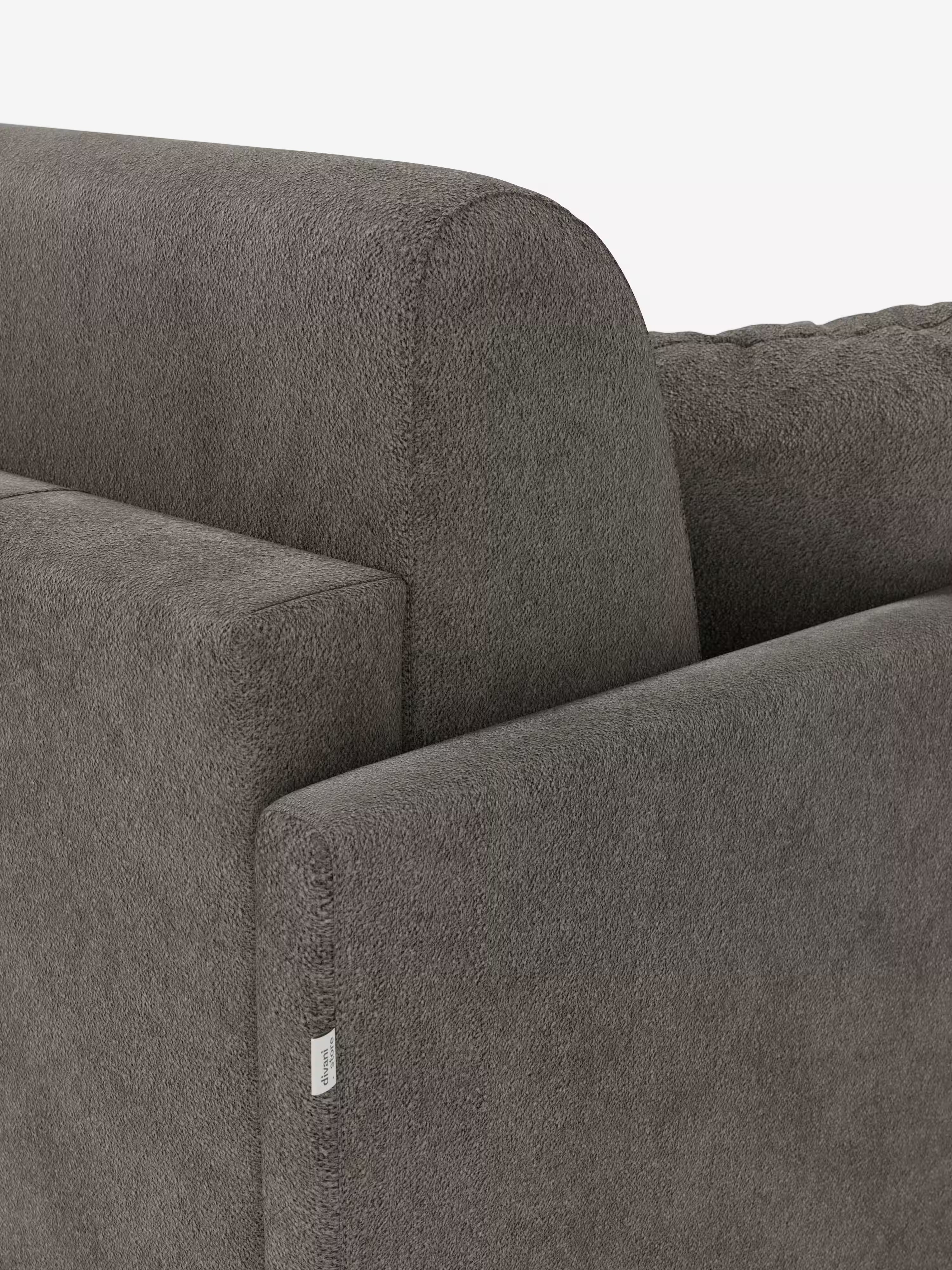 Primo piano dello schienale e dei braccioli del divano letto Tommy Divano a 2 e 3 posti matrimoniale di Divani.Store, che mette in risalto il design slanciato dei braccioli, il tessuto T33 simile al cotone, testurizzato e resistente alle macchie, e le linee pulite. Un piccolo cartellino in tessuto bianco è applicato all’angolo del bracciolo. Lo sfondo chiaro e sobrio mette in risalto i dettagli moderni del divano.