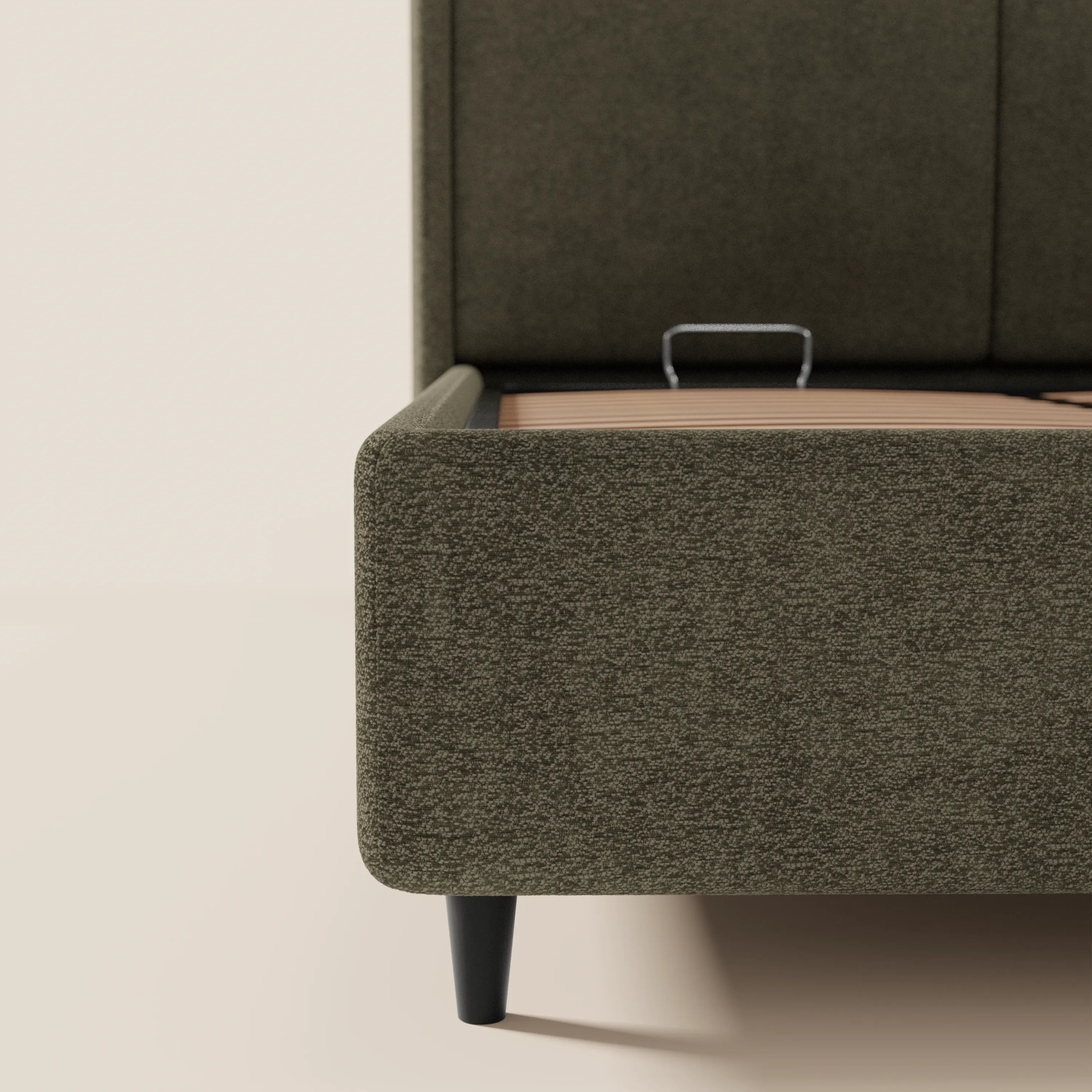 Primo piano del letto di design VALKIRIA di Letti.store in tessuto verde oliva certificato Oeko-Tex®: struttura arrotondata, testiera alta e avvolgente con 2 cuscini imbottiti, gambe affusolate nere, rete metallica e pratico contenitore integrato.