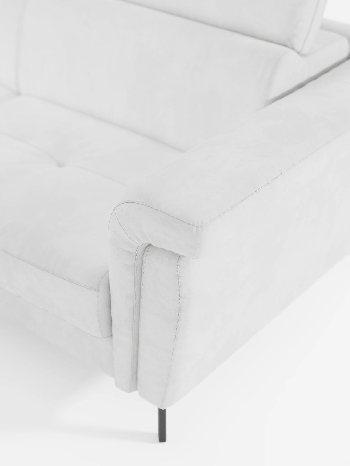 Un primo piano del divano letto angolare Capri con poggiatesta reclinabili e materasso ad alte prestazioni in tessuto vellutino smacchiabile T30 di Divani.Store, che mette in risalto il bracciolo, il cuscino di seduta e lo schienale. Il divano è rivestito in un morbido tessuto vellutato antimacchia e presenta sottili gambe in metallo nero. L’immagine mette in risalto le linee moderne e minimaliste del divano angolare, un esempio ideale di design moderno per interni contemporanei.