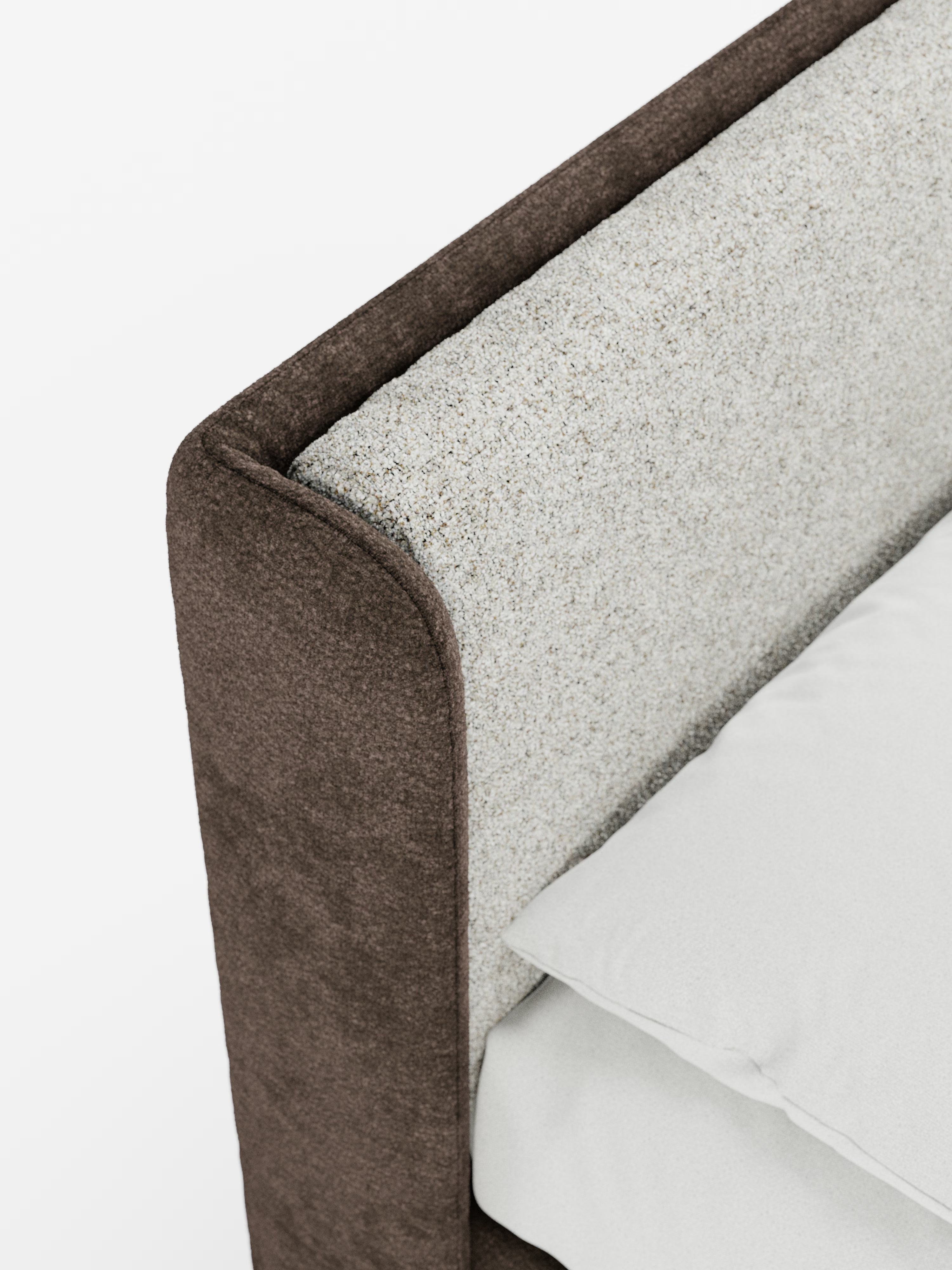 Primo piano del letto imbottito bicolore VALKIRIA con contenitore di Letti.store, caratterizzato da una testiera curva avvolgente beige con texture, cuscini dello schienale coordinati e un telaio esterno in tessuto marrone scuro a contrasto. Un cuscino bianco candido e una parte di un lenzuolo bianco giacciono ordinatamente sul materasso, in un ambiente luminoso e minimalista.