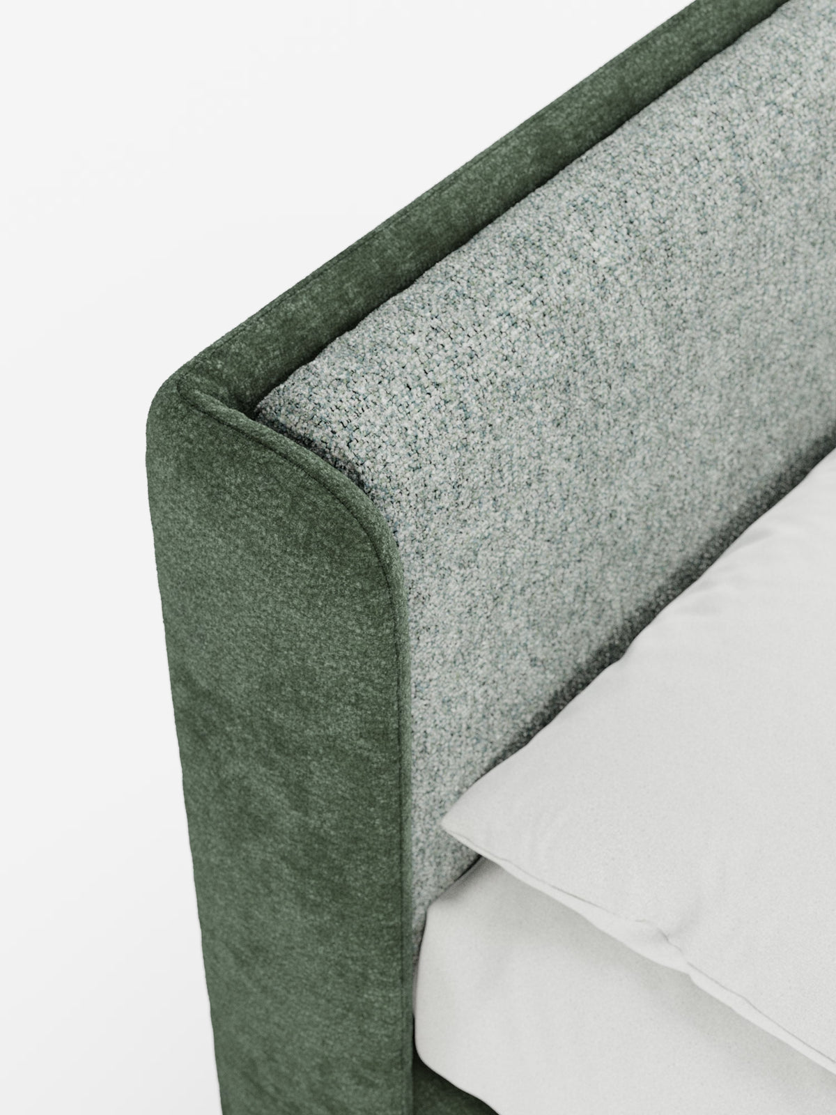 Un primo piano dell’angolo di un letto mette in risalto il modello VALKIRIA, letto imbottito bicolore con vano contenitore di Letti.store, caratterizzato da una struttura imbottita verde abbinata a un tessuto grigio chiaro testurizzato sui cuscini dello schienale e da una testiera dalla linea avvolgente. Si intravedono un cuscino bianco e una parte di un lenzuolo bianco, che sottolineano il design accogliente e moderno di questo letto bicolore con la sua elegante testiera imbottita su uno sfondo bianco e