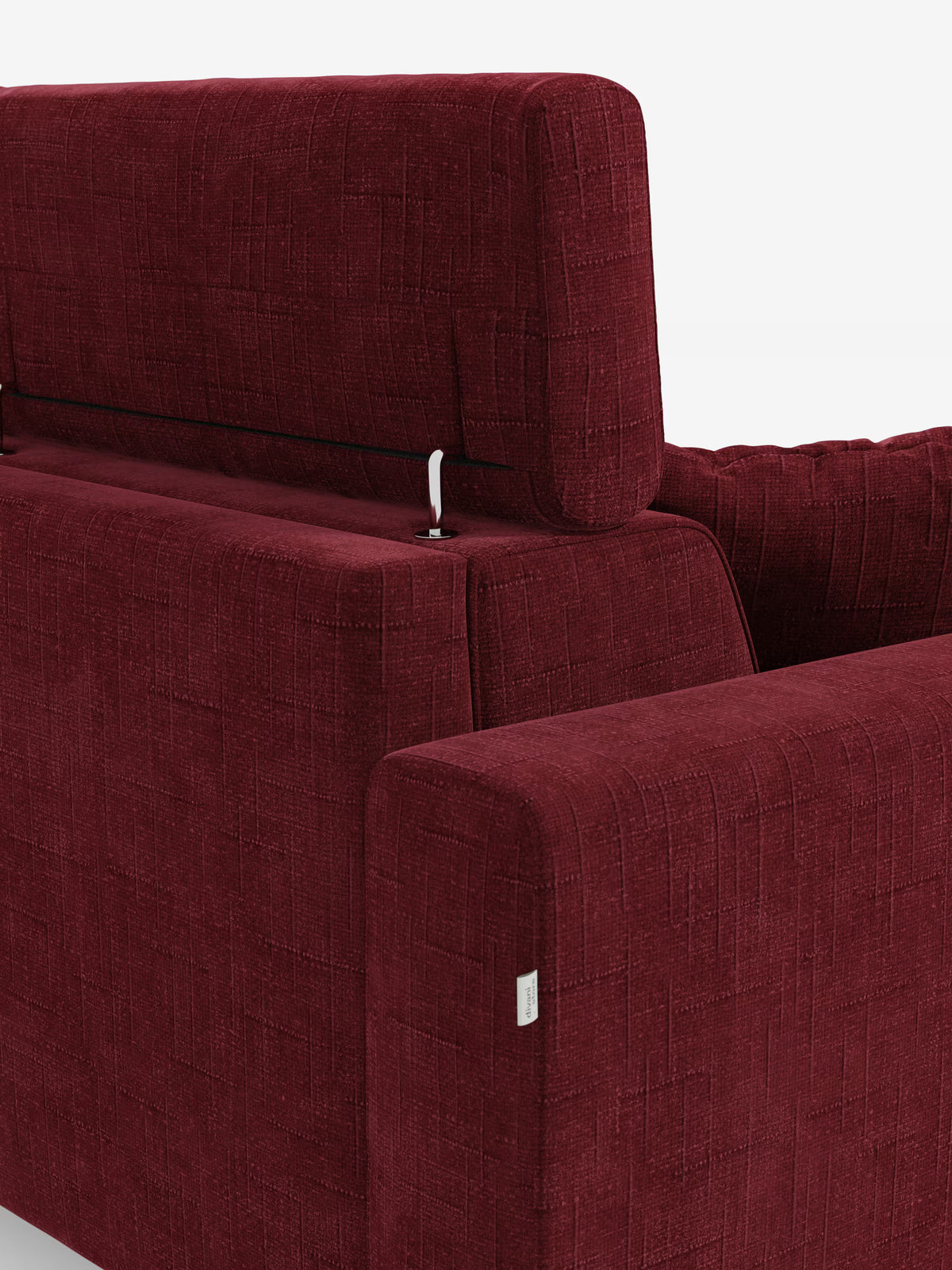Un primo piano del divano letto angolare Pegaso con poggiatesta reclinabili e penisola contenitore di Divani.Store ne mette in risalto il tessuto jacquard rosso smacchiabile T22 con finitura testurizzata. Uno dei poggiatesta regolabili è parzialmente sollevato, lasciando intravedere una cerniera in metallo argentato, mentre le linee pulite e moderne definiscono la silhouette del divano. Sull’bracciolo spicca una piccola etichetta in tessuto bianco su uno sfondo bianco a tinta unita.