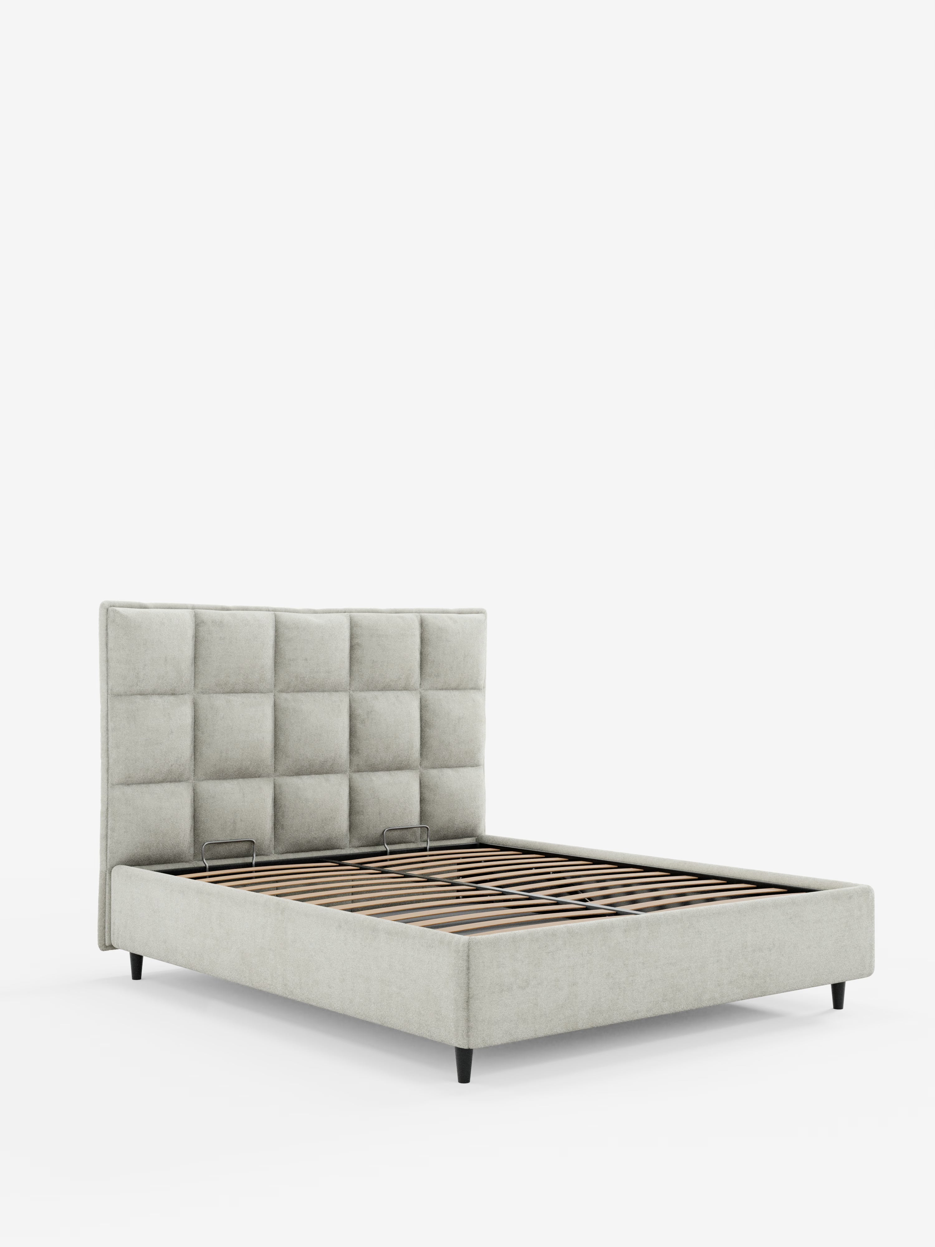 Il letto imbottito AURO con contenitore e testiera alta capitonné in ciniglia Oeko-Tex® di Letti.store presenta un moderno rivestimento in tessuto grigio chiaro, una testiera alta con effetto capitonné a motivo quadrato e robuste doghe in legno per il sostegno del materasso. Questo letto poggia su gambe corte nere ed è presentato su uno sfondo bianco a tinta unita.