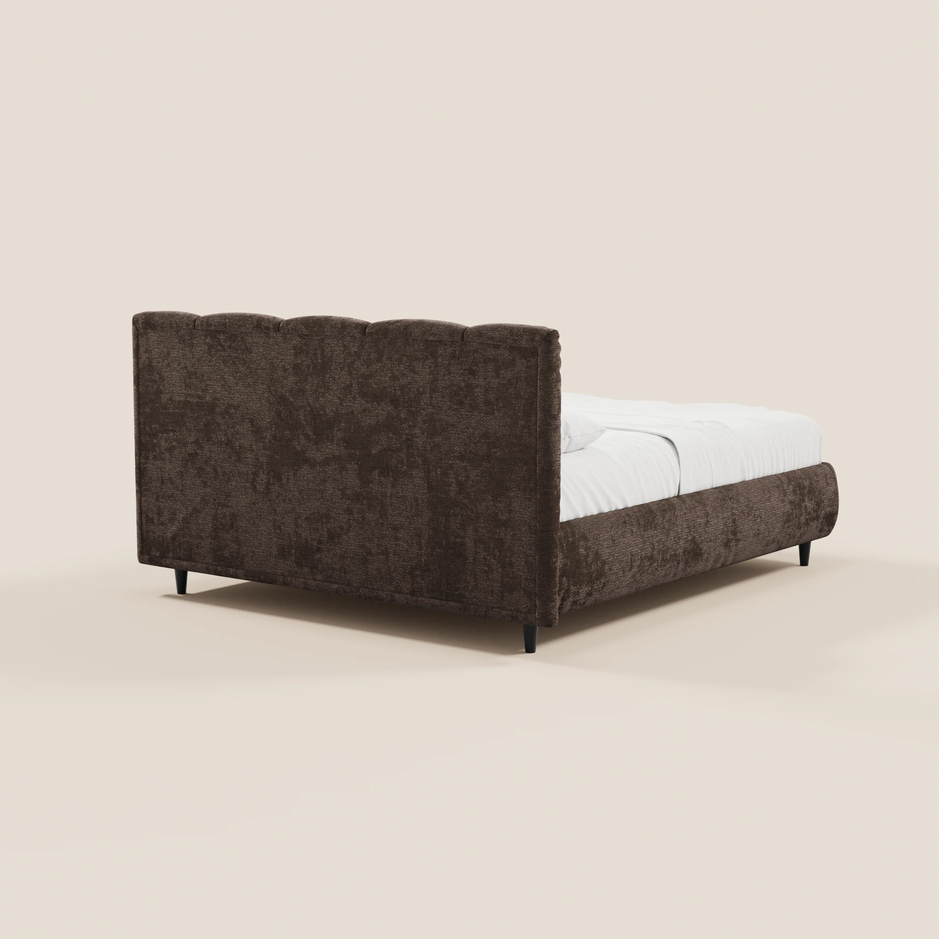 Il letto imbottito ARKAM di Letti.store presenta una testiera in tessuto marrone con cuciture verticali certificata Oeko-Tex® e una base contenitore in stile shabby chic; nella foto è raffigurato nella vista posteriore sinistra con biancheria da letto bianca, su gambe corte nere, su uno sfondo bianco sporco.