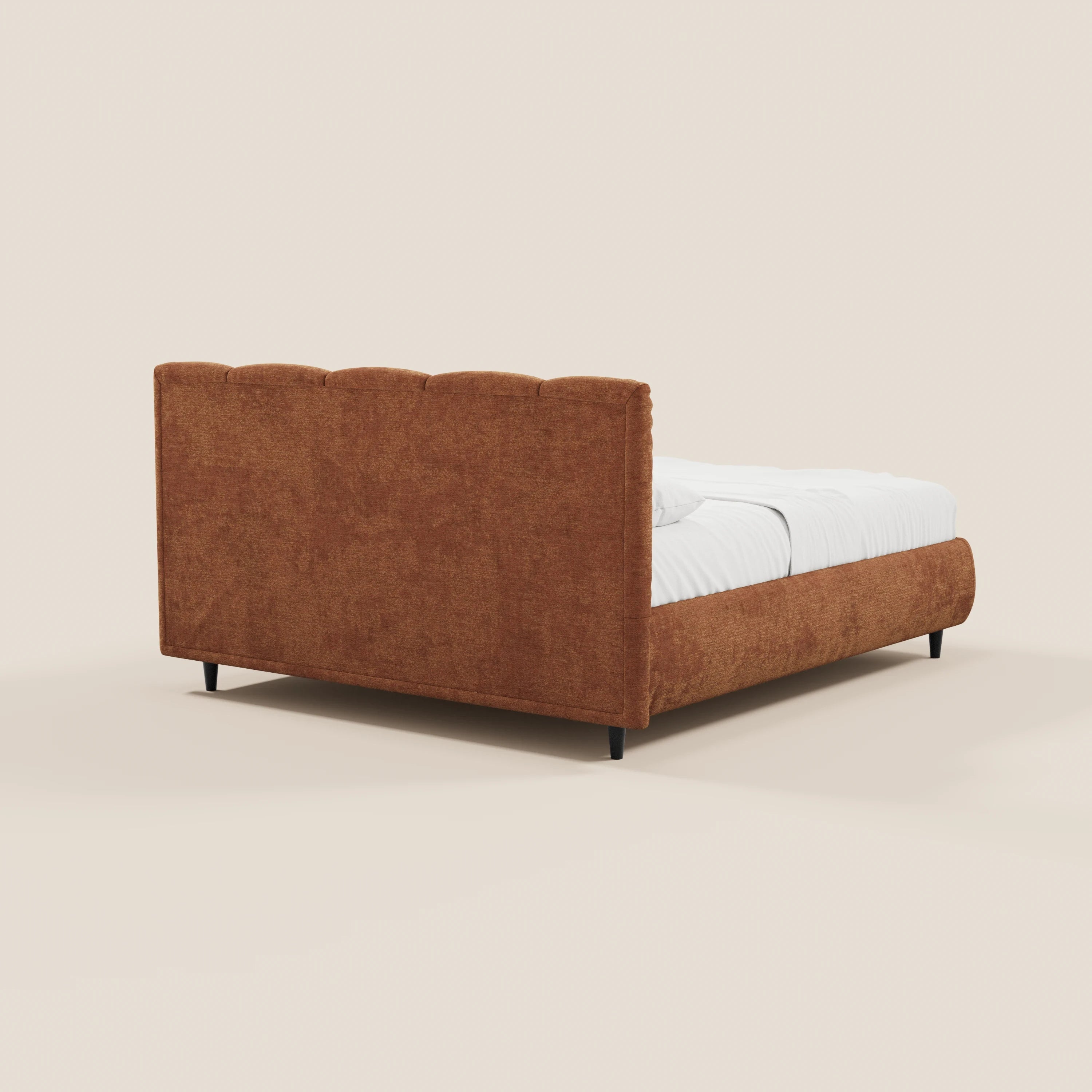 Il letto imbottito ARKAM di Letti.store presenta un tessuto color ruggine con testiera alta cucita verticalmente, pediera bassa, rivestimento certificato Oeko-Tex®, gambe nere e biancheria da letto bianca: il tutto ripreso da un’angolazione laterale posteriore su uno sfondo beige chiaro.