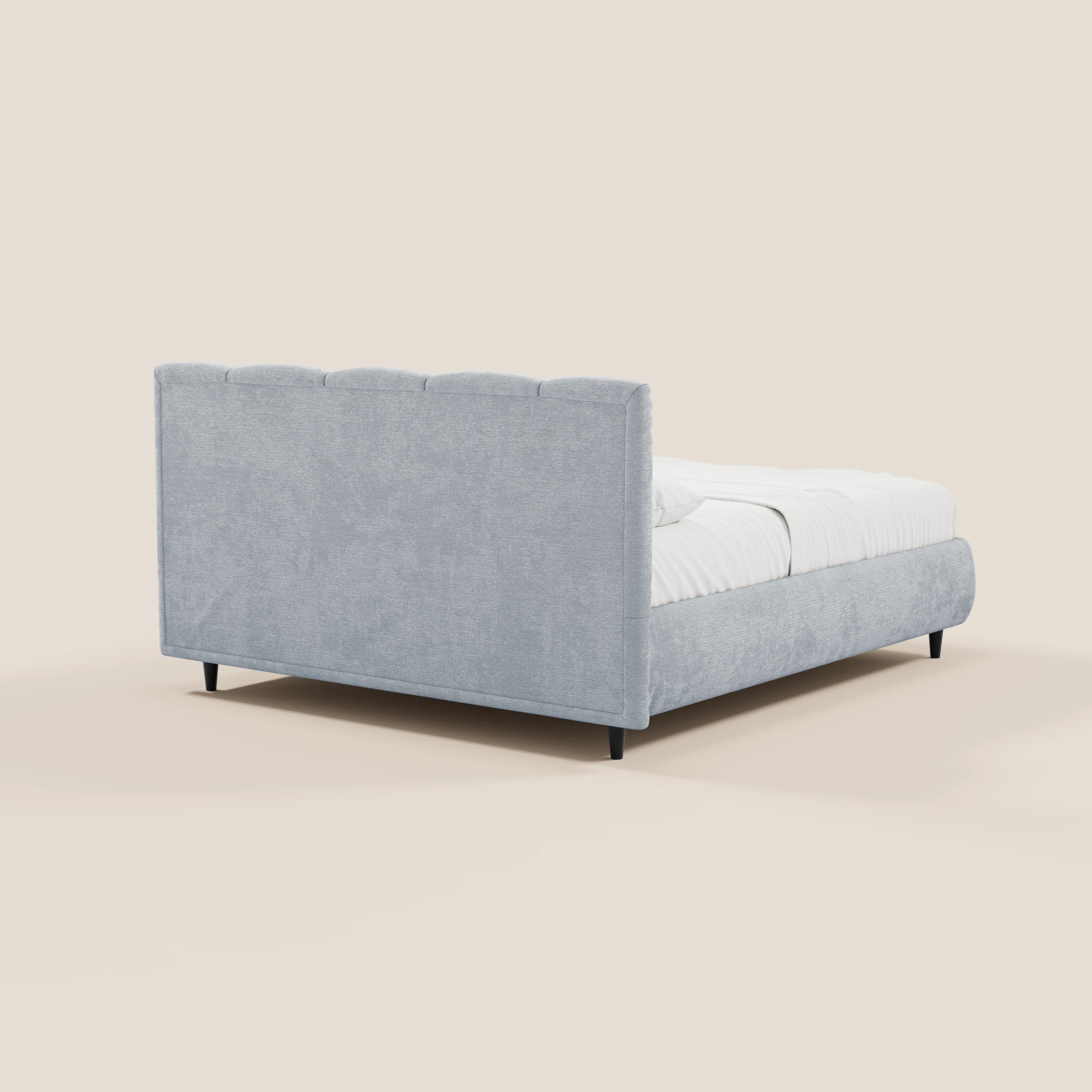 Il letto imbottito ARKAM di Letti.store, dotato di vano contenitore e testiera con lavorazione verticale in tessuto certificato Oeko-Tex®, si distingue per il suo design shabby chic e le linee pulite. Immagine che ne mostra la parte posteriore su uno sfondo beige chiaro, con gambe basse nere e biancheria da letto bianca.