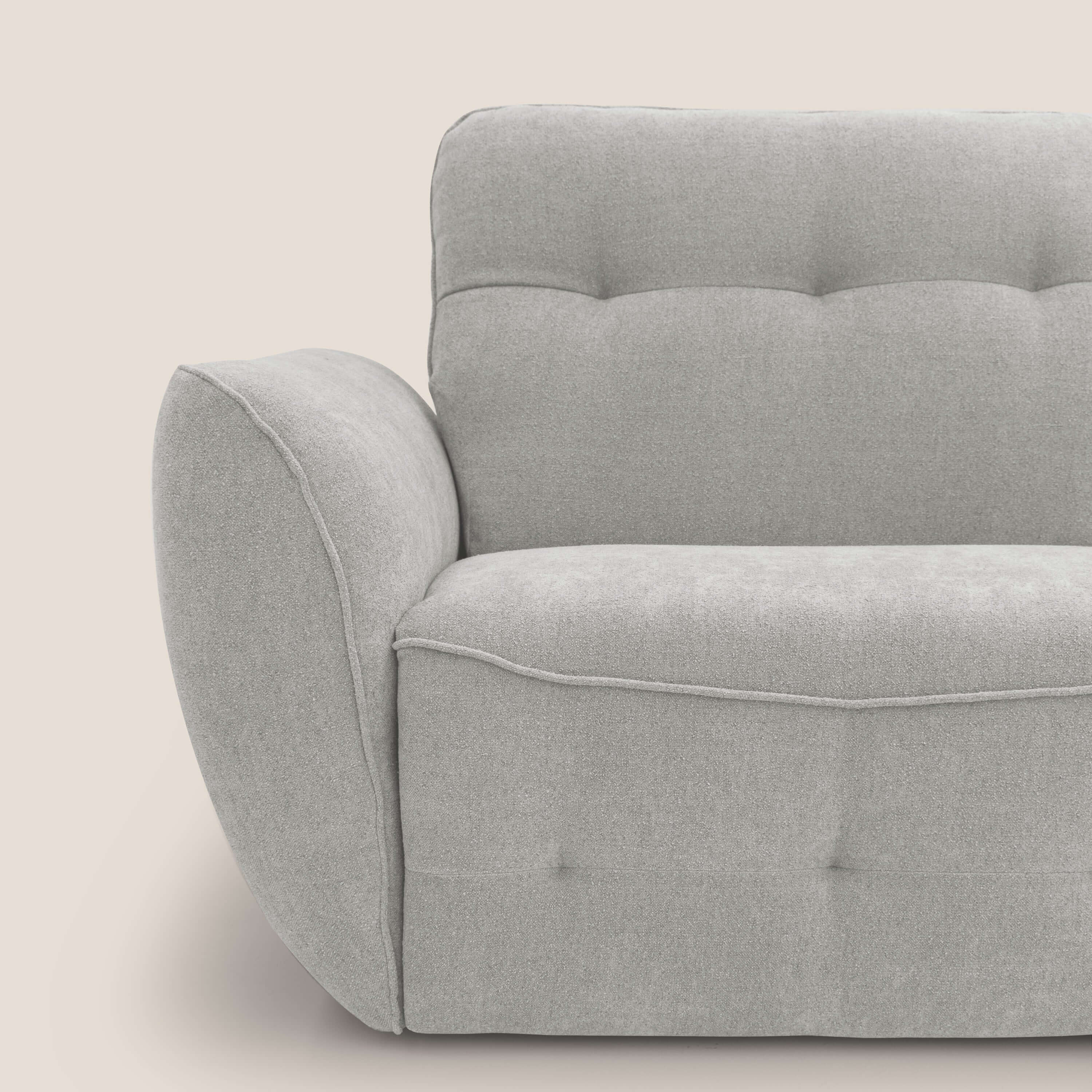 Il divano Cerbero 3 posti (208 cm) di Divani.Store in morbido bouclé impermeabile T07 grigio chiaro è caratterizzato da un design moderno e squadrato, cuscini trapuntati, ampi braccioli e cuciture a vista su uno sfondo beige neutro.