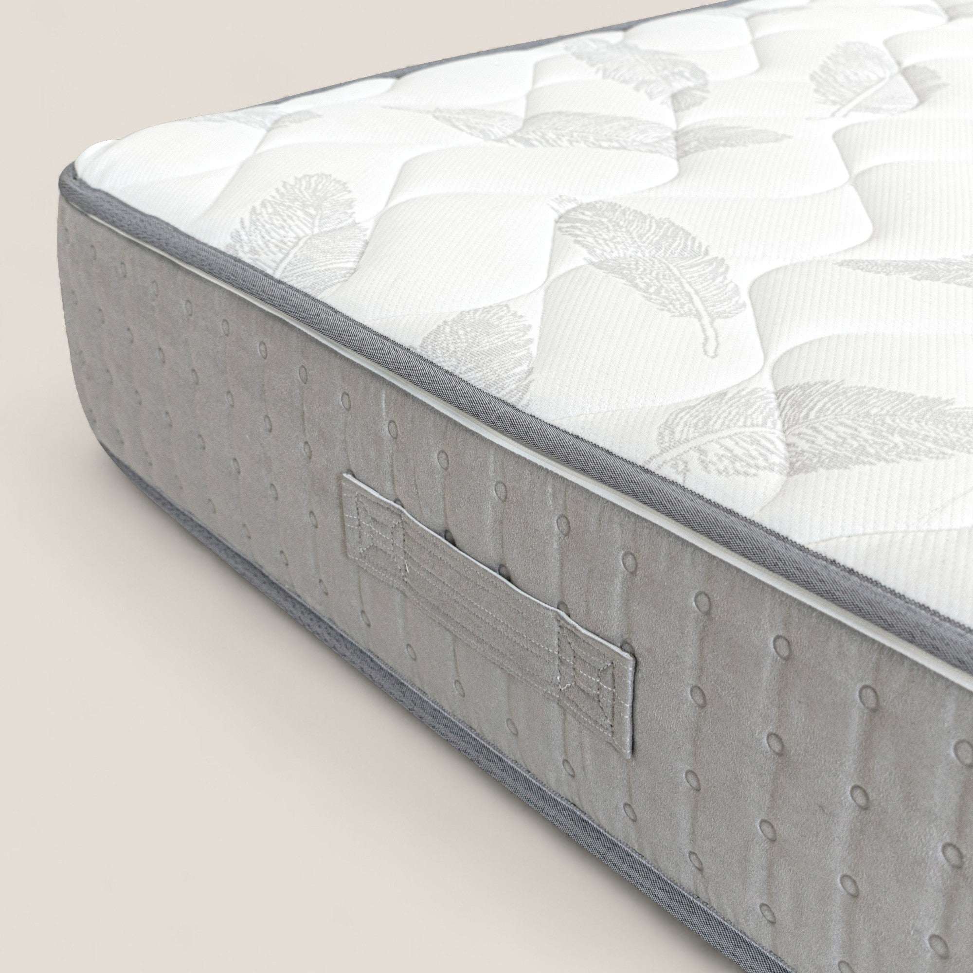 Un primo piano del Divani.Store AERION - Materasso Ortopedico in Memory & Aquapur mostra un piano trapuntato bianco con motivi di piume grigio chiaro, un pannello laterale grigio con maniglia in tessuto cucito, una texture a puntini e uno sfondo beige chiaro.