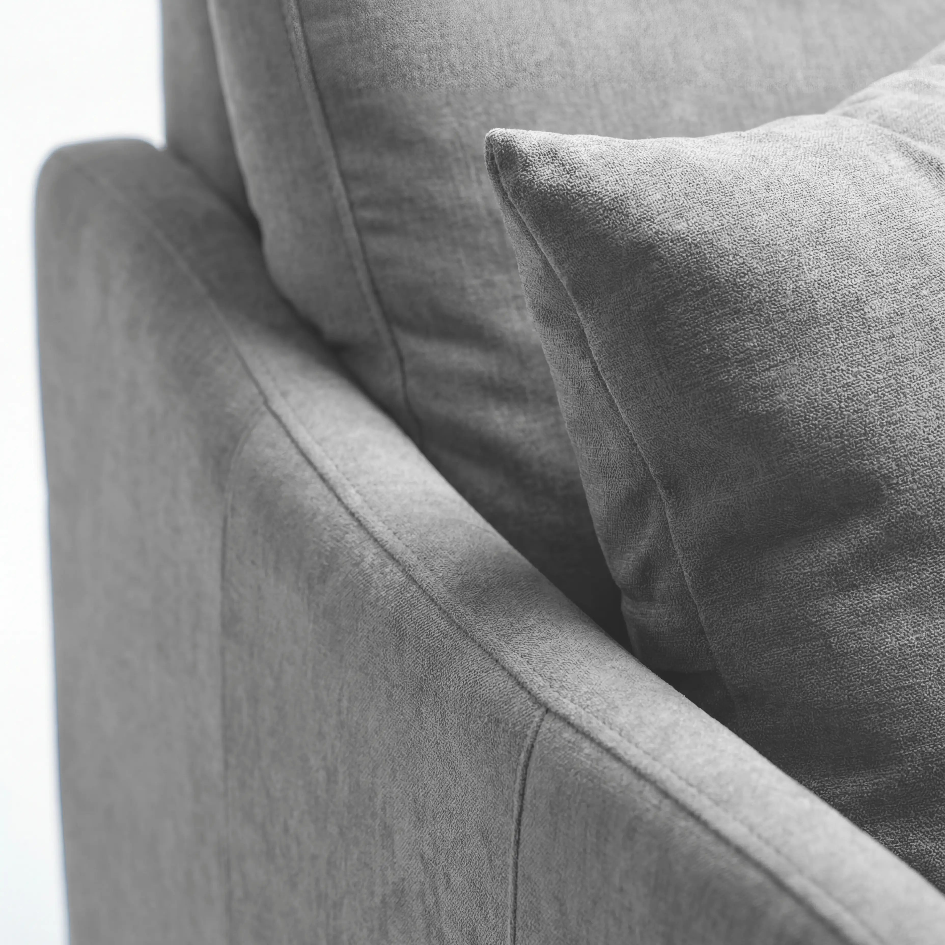 Primo piano del divano letto a 3 posti Lodovico di Divani.Store in grigio chiaro, caratterizzato da un angolo con bracciolo e schienale, un cuscino coordinato, che mette in risalto il morbido tessuto certificato Oeko-Tex e resistente alle macchie, con cuciture pulite.