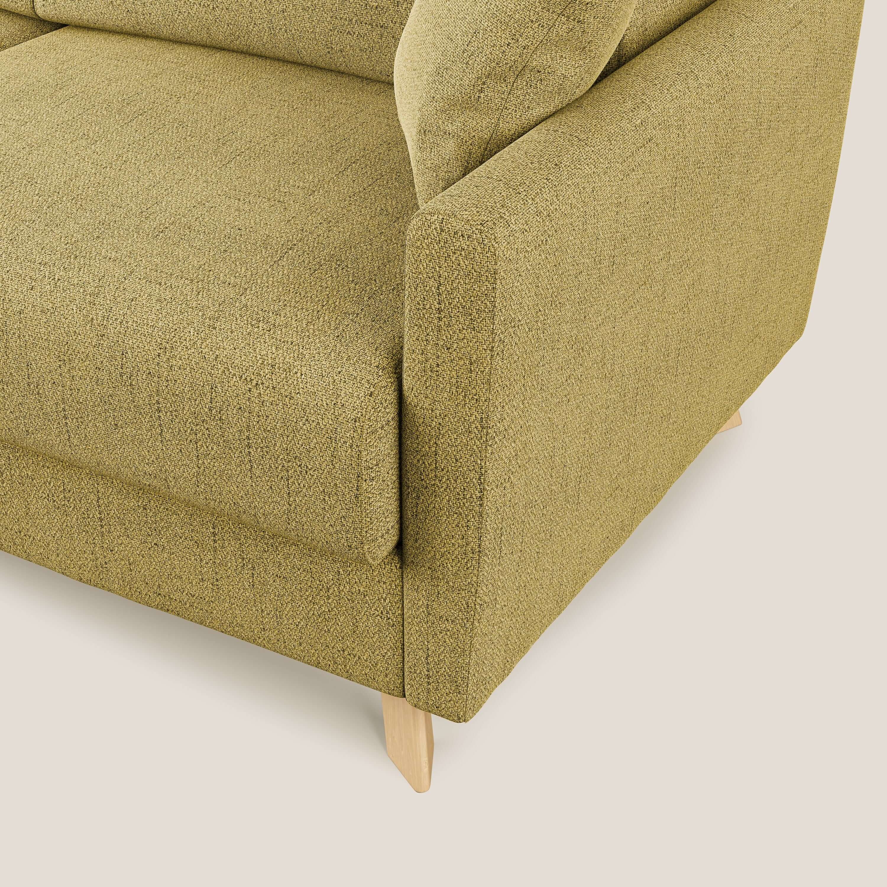 Un primo piano del divano letto angolare Edgar da 243 cm sinistro di Divani.Store in tessuto impermeabile T03 giallo mostra il bracciolo, la seduta e lo schienale con rivestimento strutturato su corte gambe in legno chiaro su uno sfondo bianco sporco.