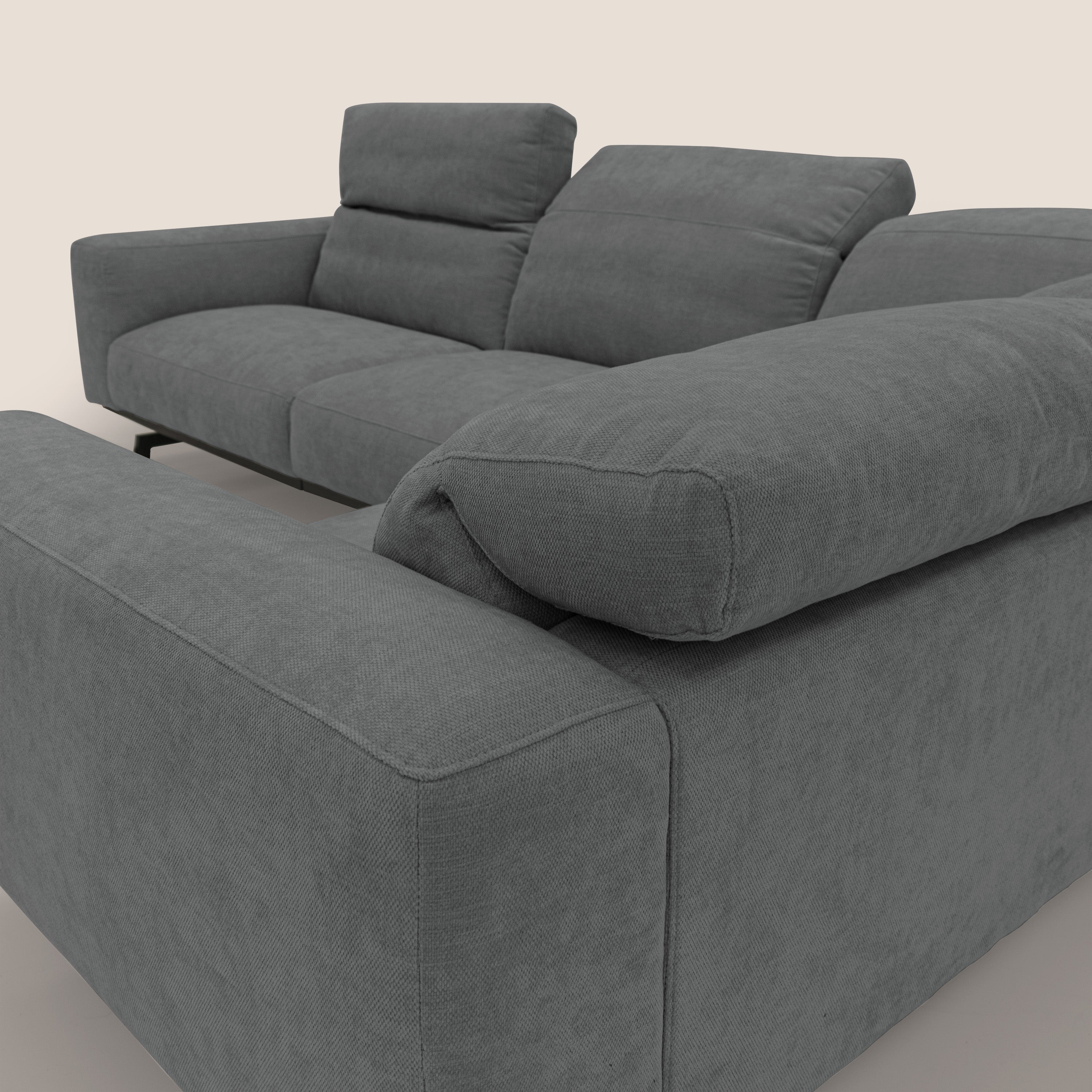 Il divano Sakura in piuma d'oca angolare REVERSIBILE di Divani.Store è caratterizzato da ampi braccioli, morbidi cuscini e due poggiatesta regolabili in soffice tessuto impermeabile grigio T14, raffigurato nell'angolo posteriore su corte gambe nere su sfondo chiaro.