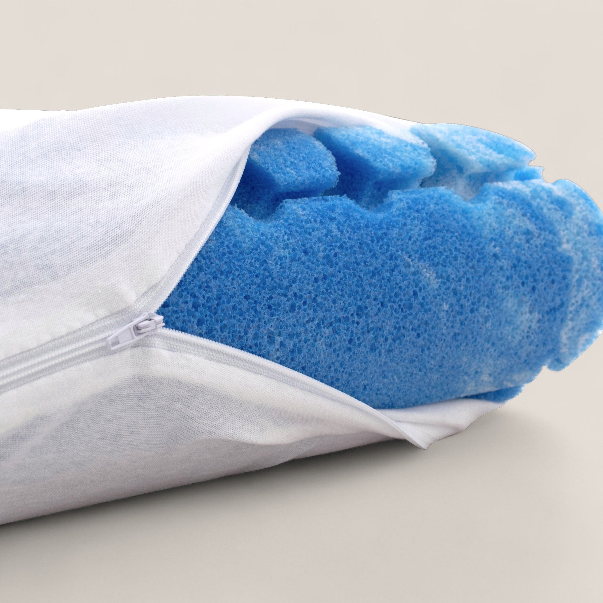Un primo piano del copricuscino con cerniera AERION-BREEZE di Divani.Store lo mostra parzialmente aperto, rivelando un'imbottitura in Memory Gel blu dall'aspetto strutturato e arioso all'interno del tessuto bianco liscio, su uno sfondo beige semplice.