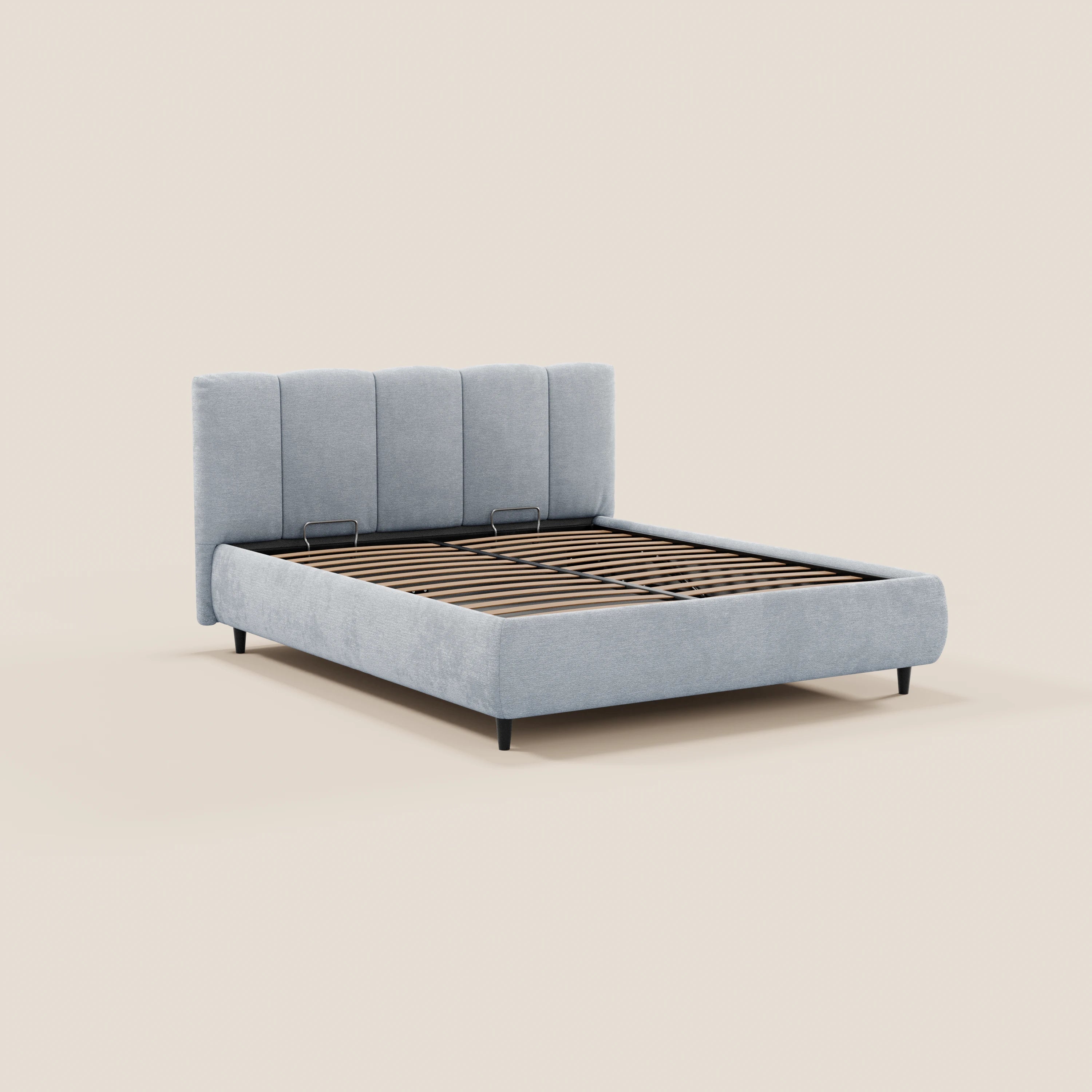 Il letto imbottito ARKAM di Letti.store è realizzato con un tessuto grigio chiaro certificato Oeko-Tex®, presenta una testiera con cuciture verticali, doghe in legno a vista, gambe nere e un vano contenitore. Il suo design shabby chic risalta sullo sfondo beige. Materasso non incluso.