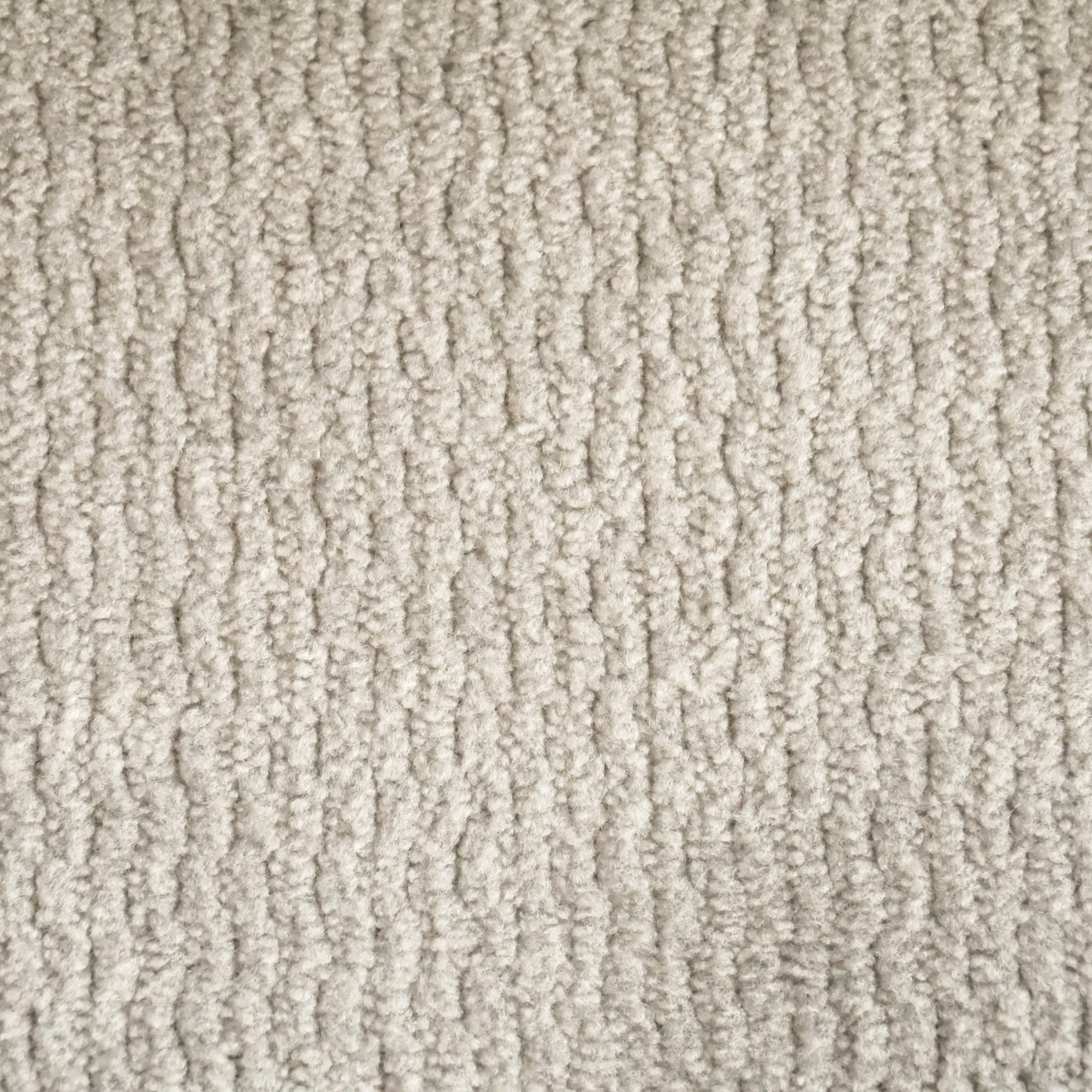 Primo piano del tappeto T32 Kendal di Divani.Store: un tappeto beige in morbido tessuto a coste con vello ad anello e disegno verticale ondulato. Il trattamento impermeabile e antimacchia ne esalta l'aspetto strutturato e le sottili variazioni di colore.
