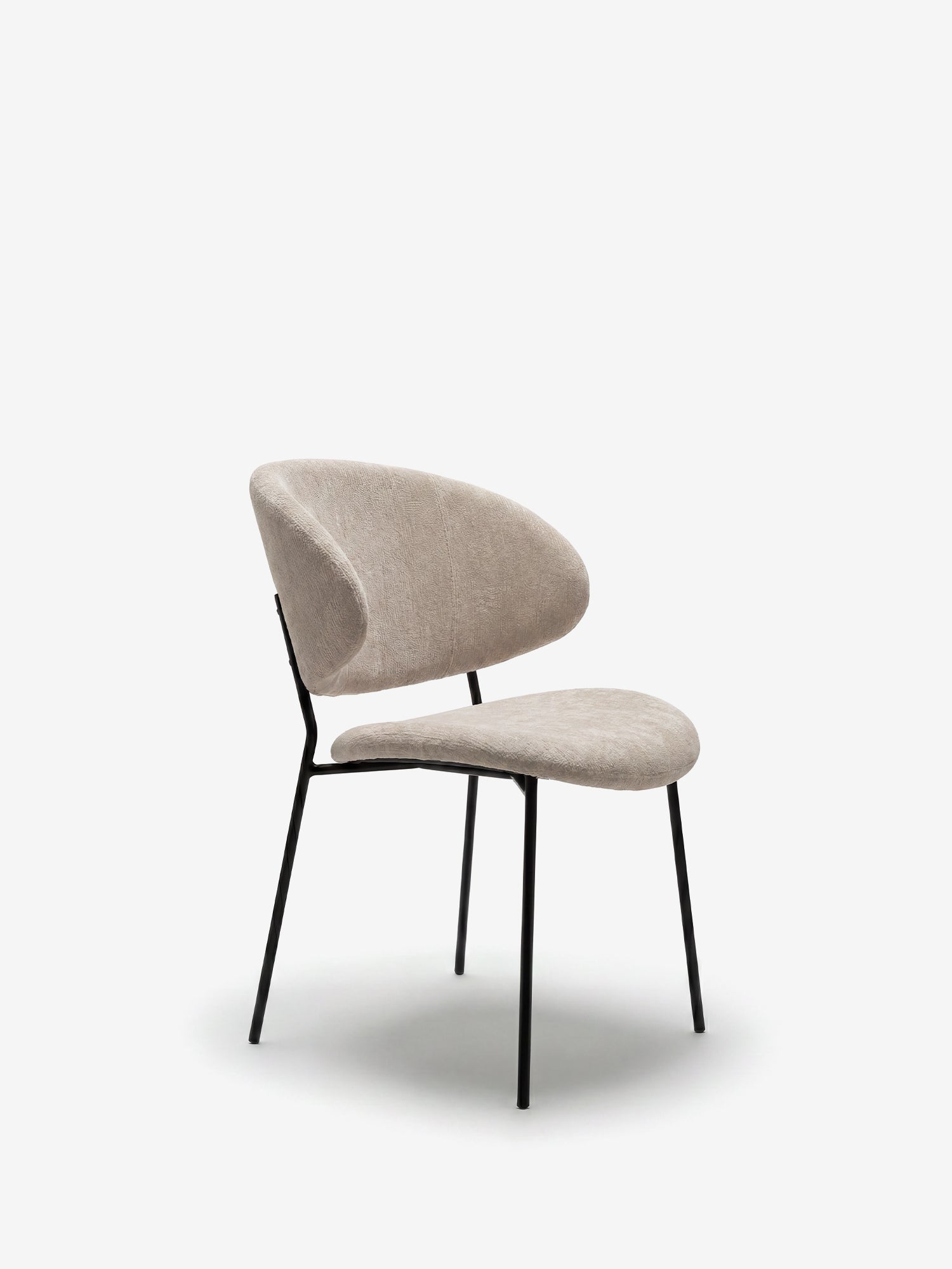 La sedia La Bruma di Divani.Store presenta un elegante tessuto goffrato beige su uno schienale avvolgente e una seduta curva, completata da sottili gambe in metallo nero e linee minimaliste, perfetta per gli ambienti moderni.