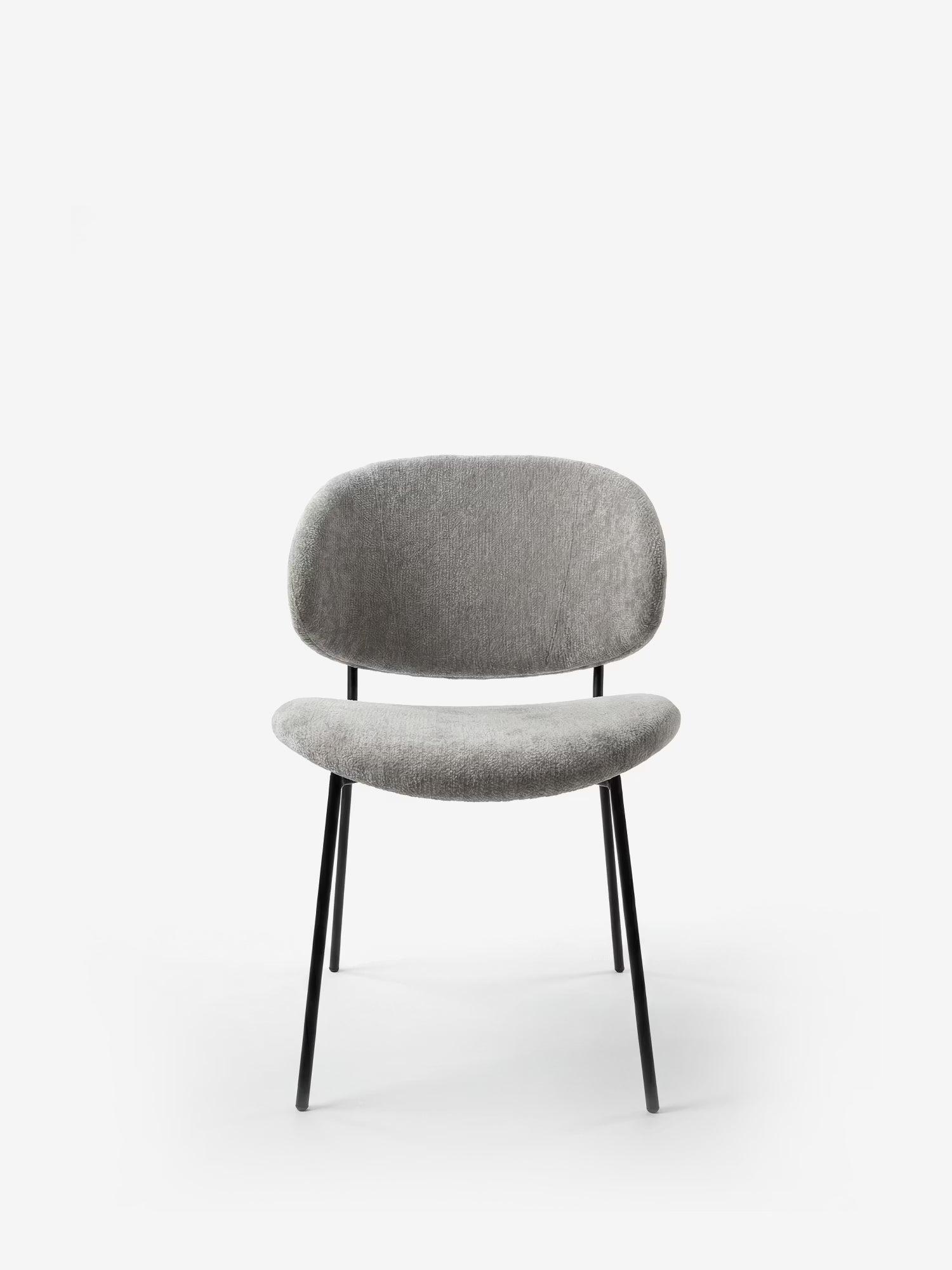 La sedia Bruma di Divani.Store è caratterizzata da un elegante tessuto goffrato, uno schienale avvolgente e gambe in metallo nero dal design minimalista, ideale per ambienti moderni.