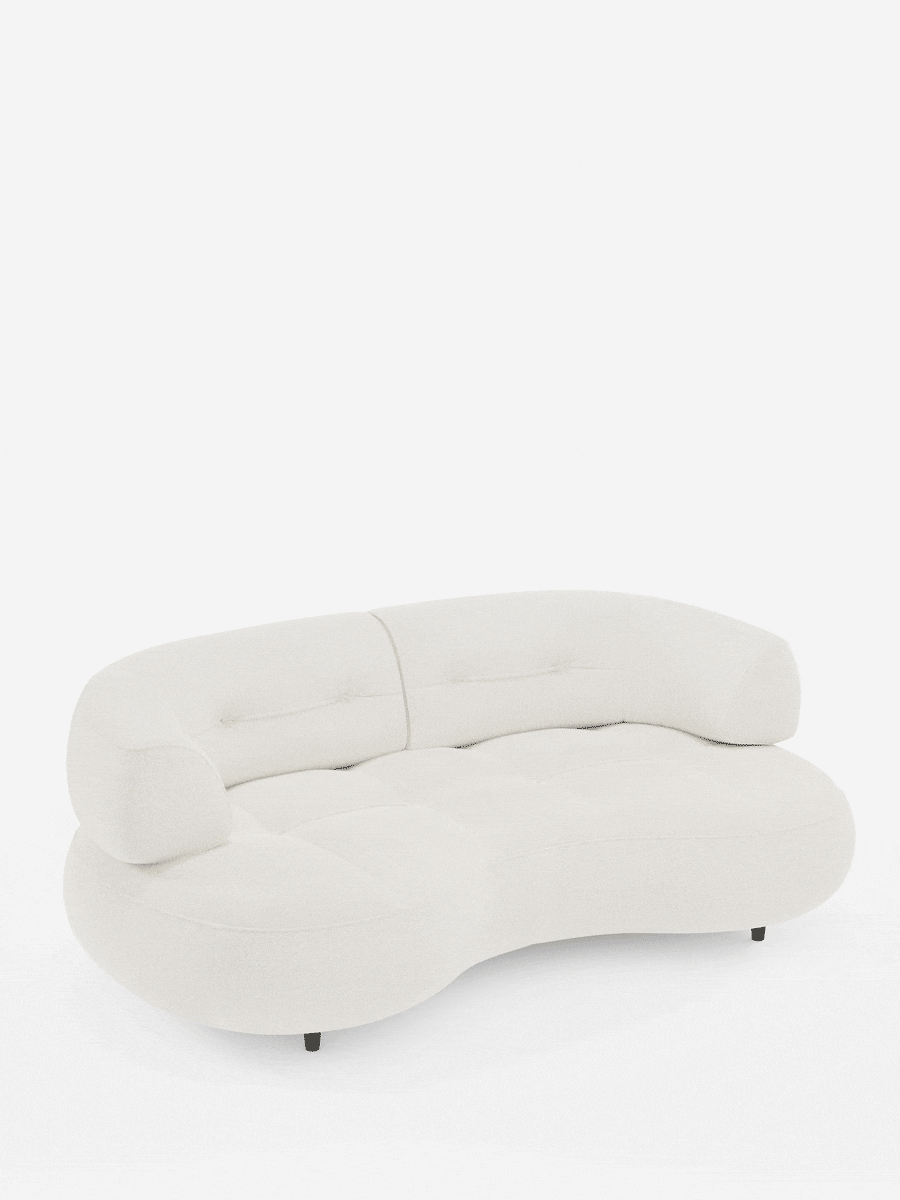 Un divano Curvo a fagiolo a 3 posti color crema, modello Croissant, con schienali traslanti in morbido tessuto effetto cotone smacchiabile T33, caratterizzato da una forma a mezzaluna, schienale basso trapuntato, bordi arrotondati e piccoli piedini scuri su sfondo bianco.