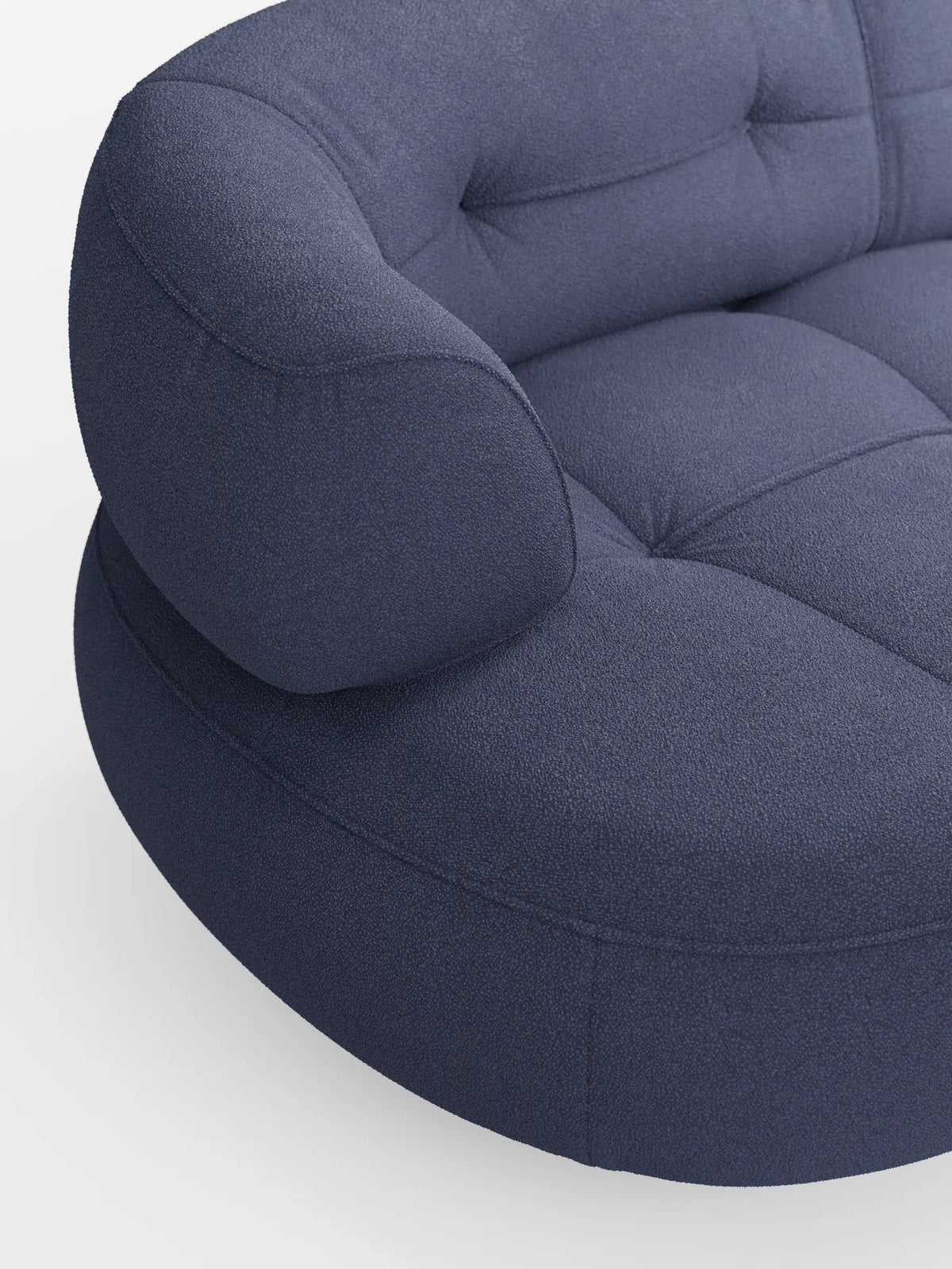 Un divano angolare Croissant blu scuro dal design a fagiolo e schienali scorrevoli, rivestito in morbido tessuto effetto cotone smacchiabile T33, caratterizzato da una silhouette sinuosa e organica, da bottoni a capitonné e da un tessuto testurizzato su uno sfondo grigio chiaro.