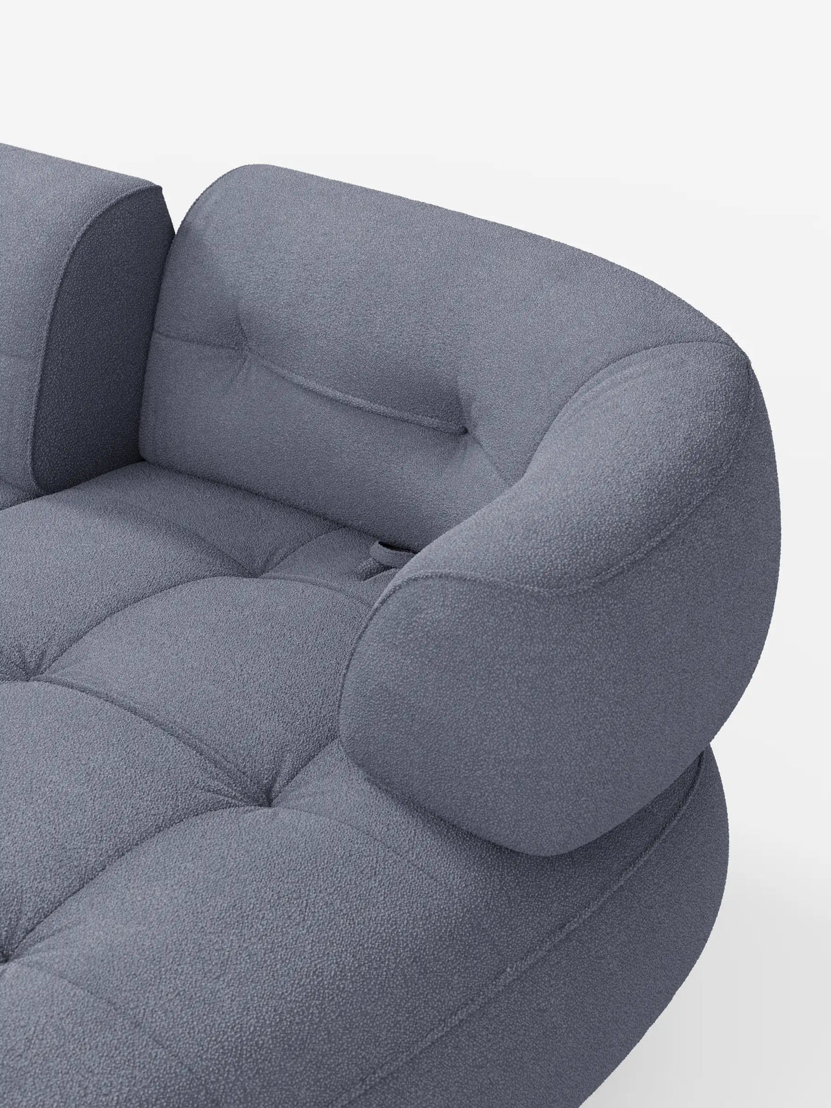 Un divano angolare Croissant dalla forma ricurva a fagiolo, con schienali scorrevoli rivestiti in morbido tessuto effetto cotone smacchiabile T33, in tessuto blu ardesia testurizzato con cuscini arrotondati e trapuntatura su sfondo a tinta unita.