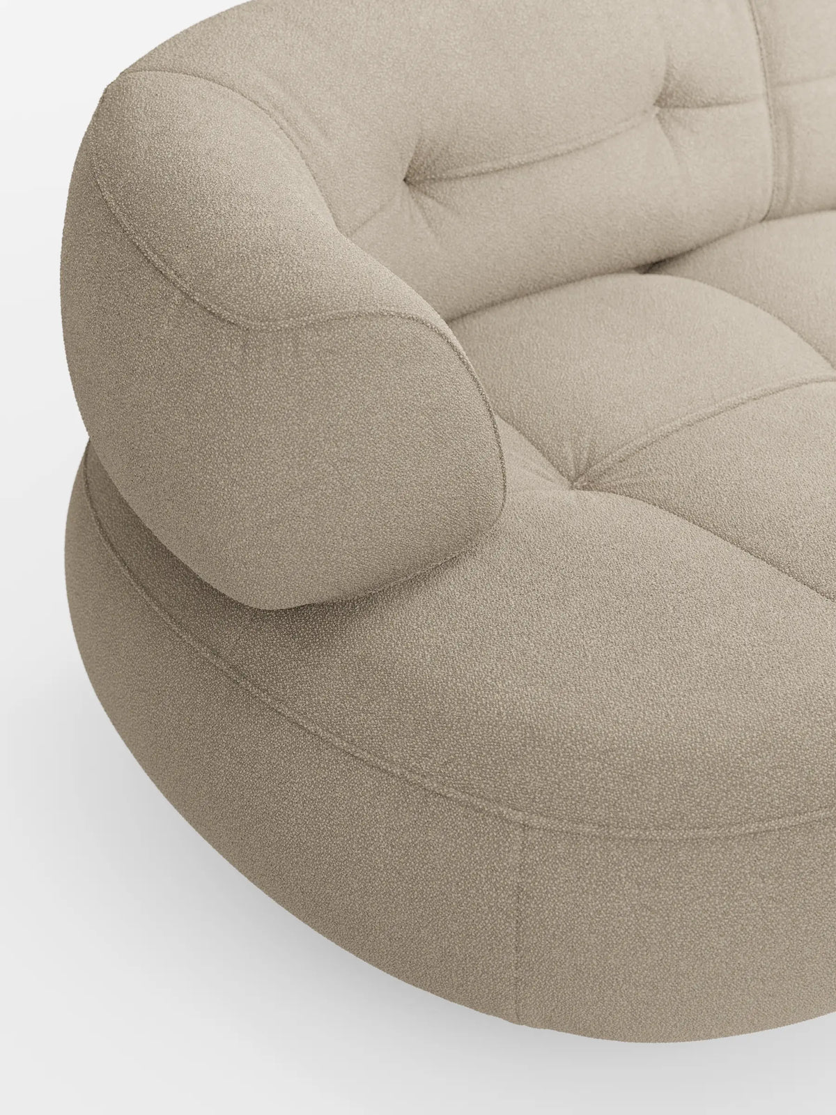 Un divano angolare Croissant color beige dal design a forma di fagiolo e con schienali scorrevoli, rivestito in morbido tessuto effetto cotone smacchiabile T33, caratterizzato da una forma curva e organica, da un rivestimento trapuntato e da braccioli bassi integrati su uno sfondo bianco sporco.