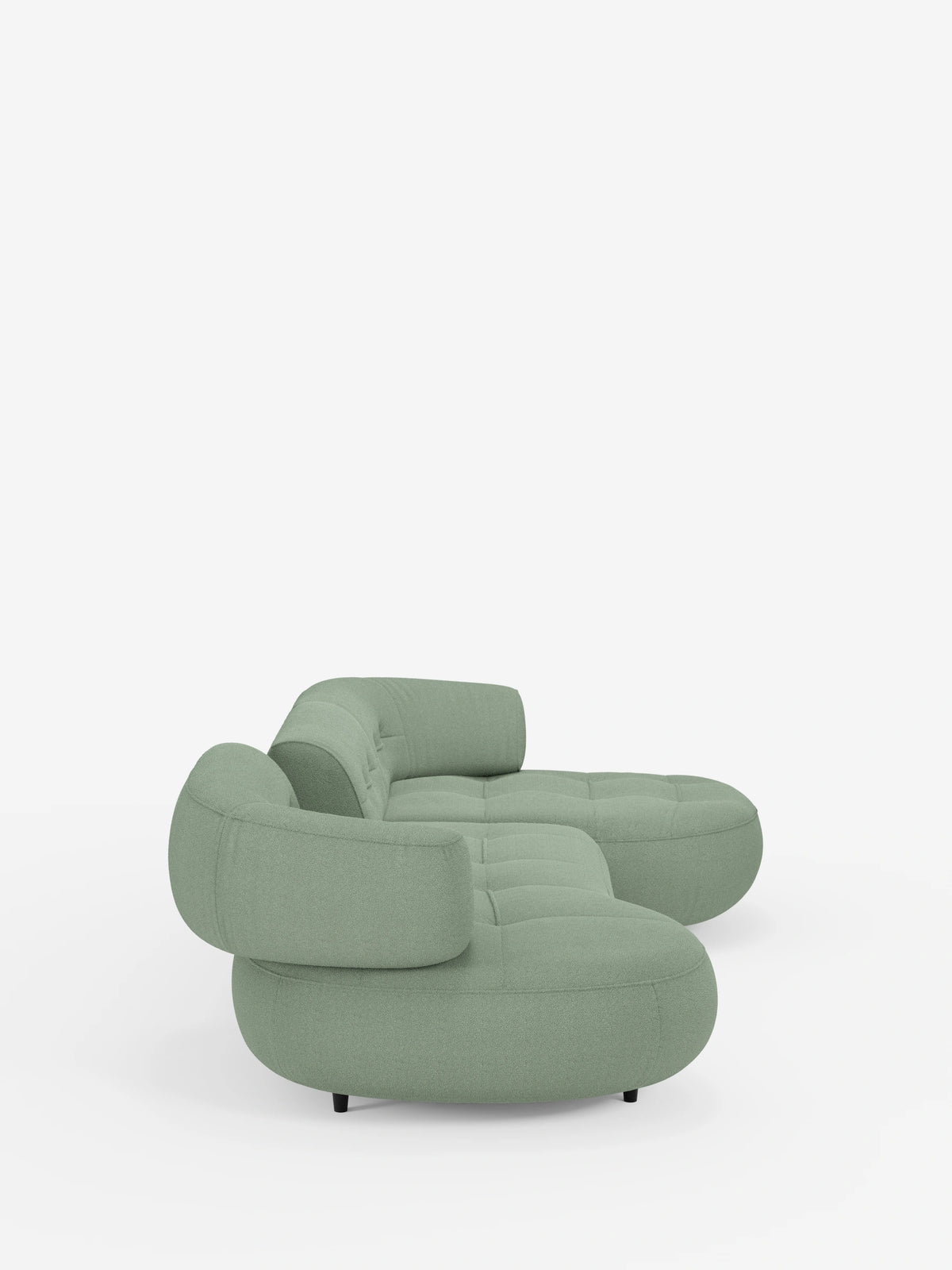 Un divano angolare Croissant dalle linee curve, color verde salvia, dal design a fagiolo e con schienali regolabili in morbido tessuto effetto cotone smacchiabile T33, caratterizzato da forme arrotondate, dettagli trapuntati sulla seduta e schienali regolabili su uno sfondo bianco.