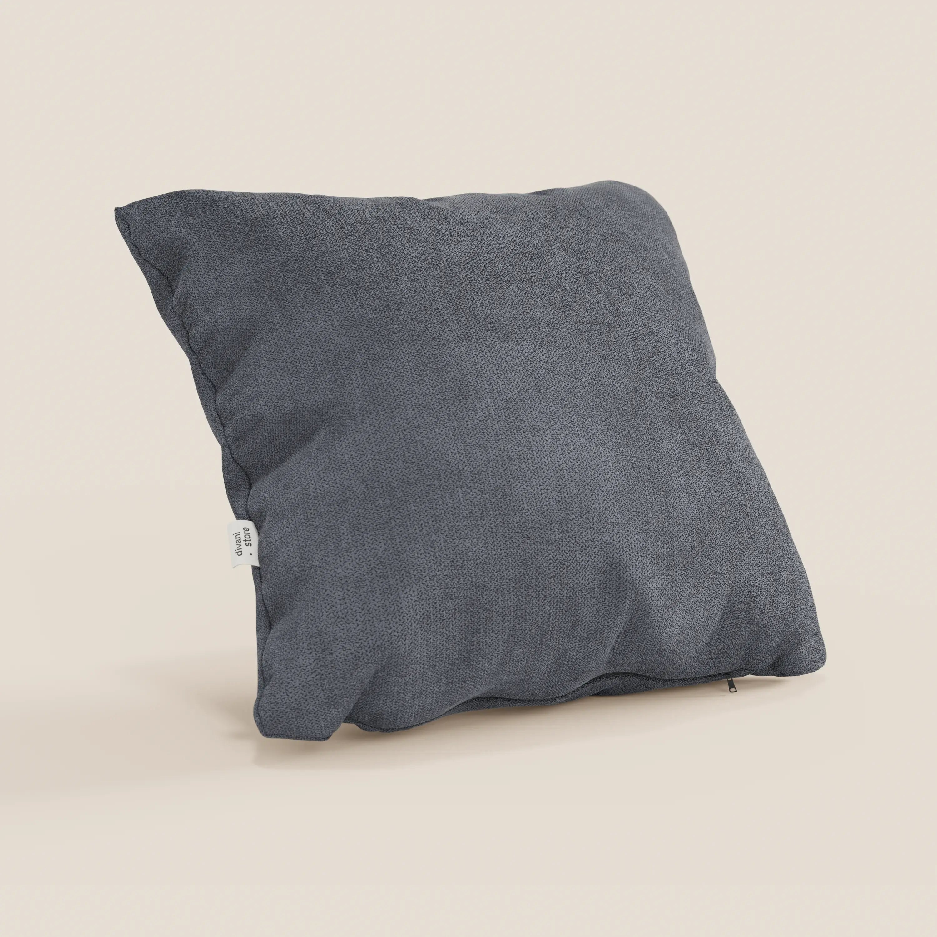 Un cuscino quadrato Destiny di Divani.Store in morbido tessuto impermeabile T02 grigio poggia su una superficie beige. Una targhetta bianca decora la cucitura sinistra e una cerniera è parzialmente visibile sul fondo della fodera lavabile.