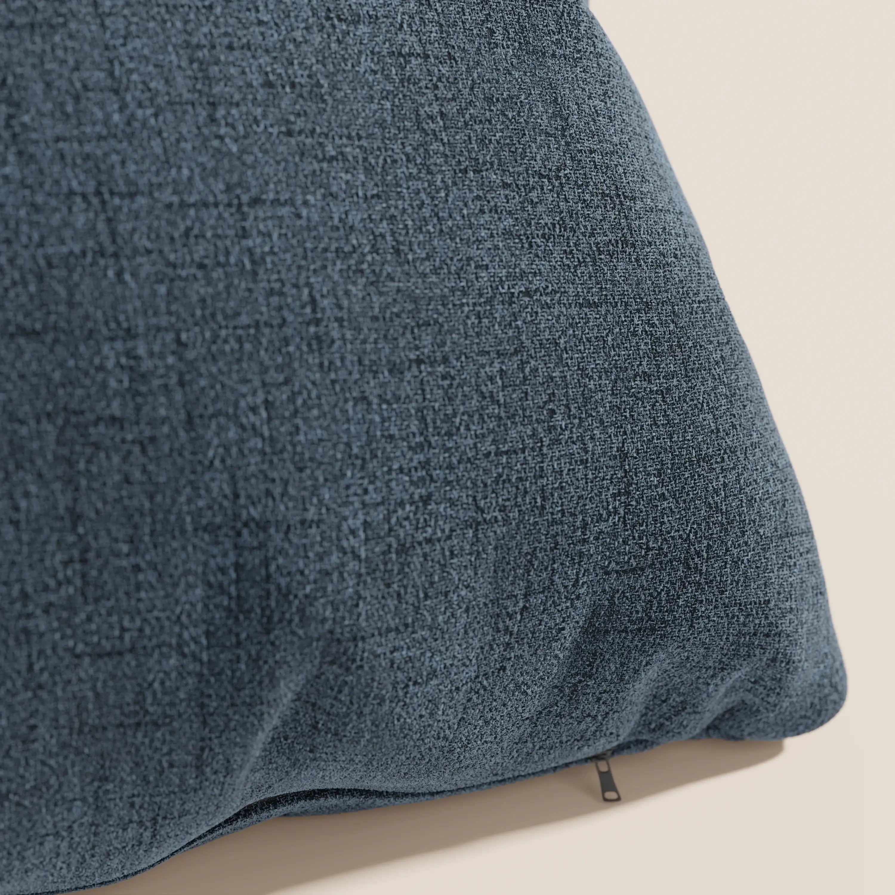 Primo piano del cuscino impermeabile Felis T03 blu di Divani.Store, caratterizzato da una superficie morbida e intrecciata con un sottile motivo a griglia e una cerniera parzialmente visibile, su uno sfondo beige chiaro.