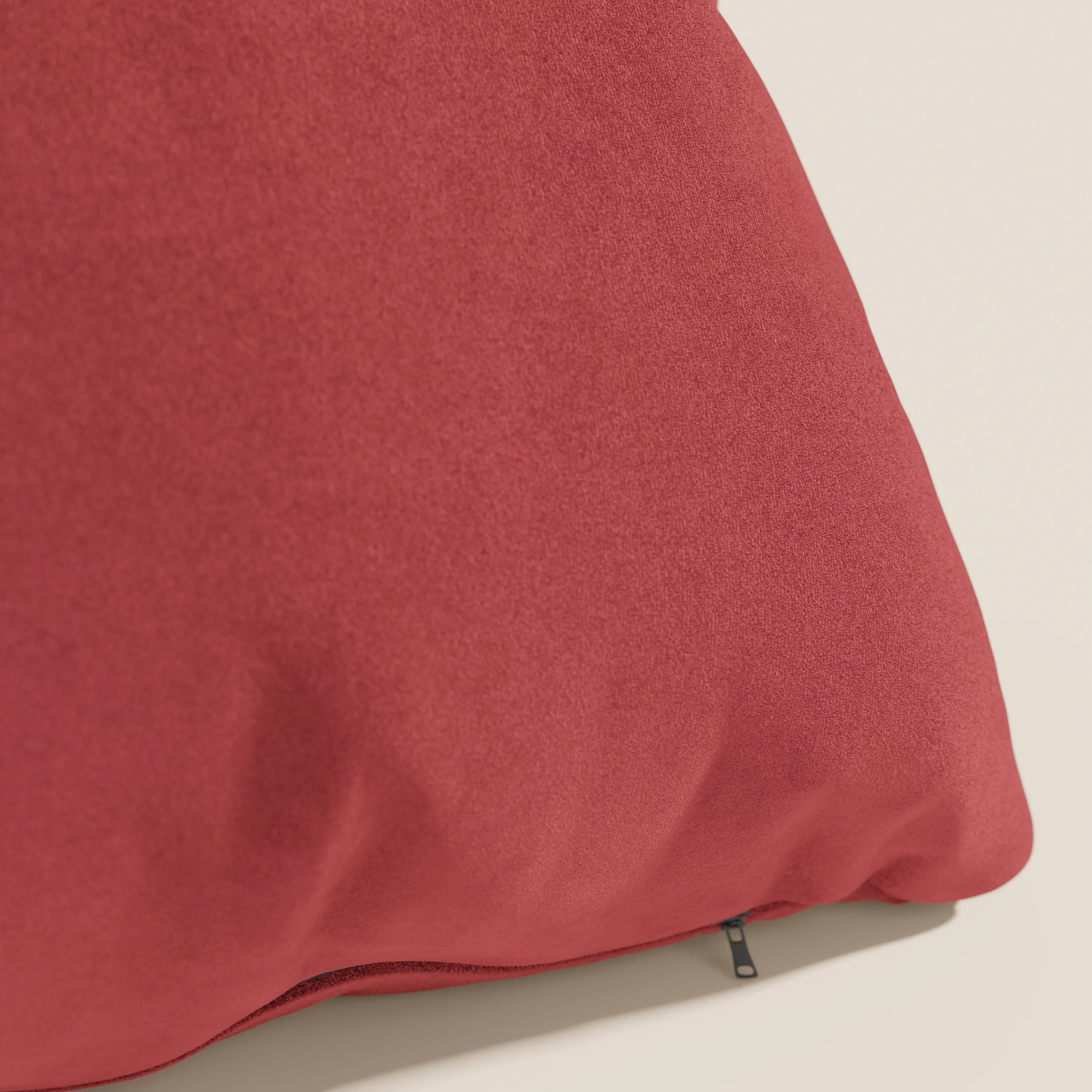 Un primo piano del cuscino Jazz di Divani.Store, presentato in smacchiabile T11 rosso microfibra tecnica. La morbida copertina rossa presenta leggere rughe e un piccolo tiretto nero, su uno sfondo crema chiaro.