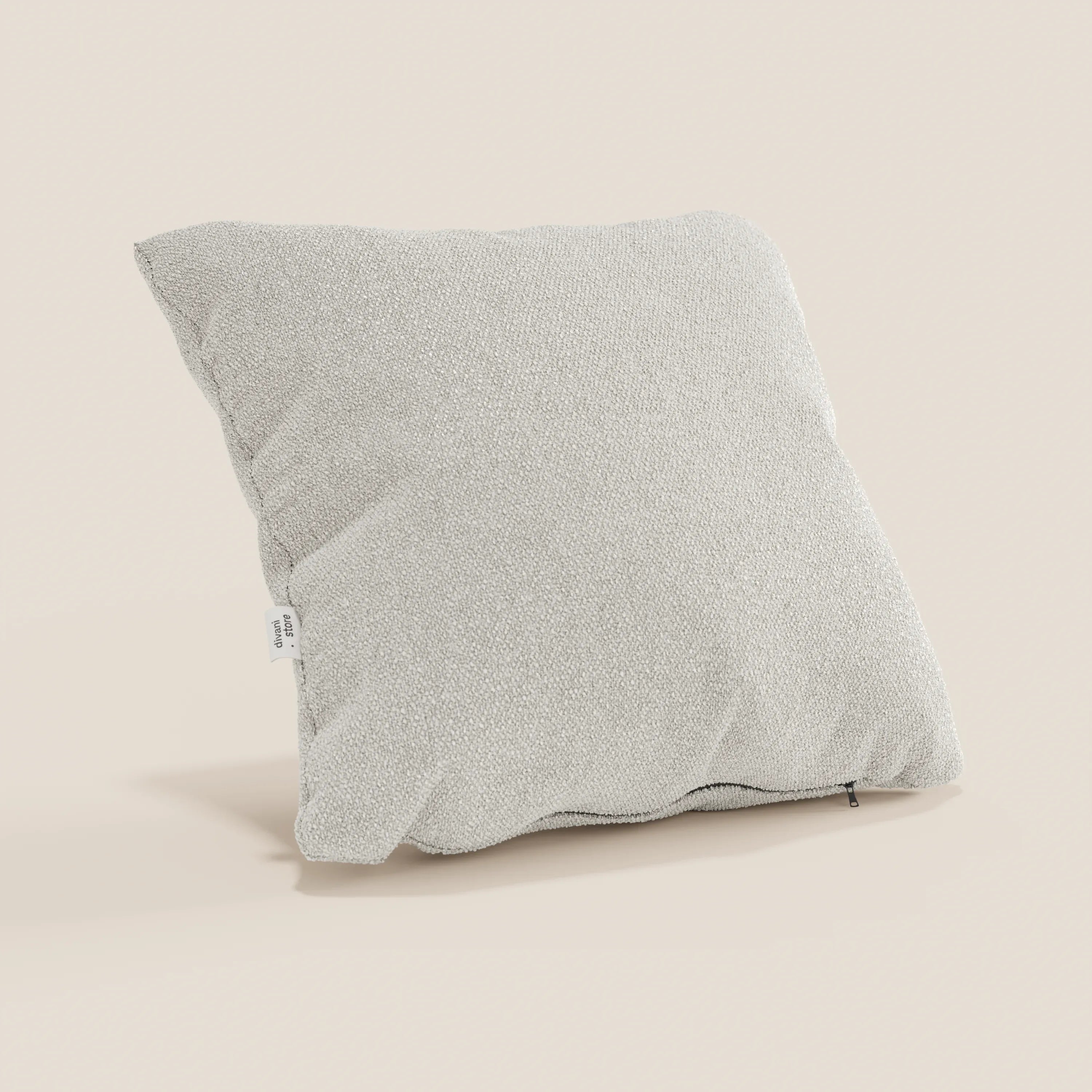 Un cuscino Lambada di Divani.Store in tessuto T33 grigio chiaro, simil-cotone, antimacchia e impermeabile, poggia su uno sfondo beige, con un'etichetta bianca su una cucitura e una discreta cerniera lungo il bordo inferiore.