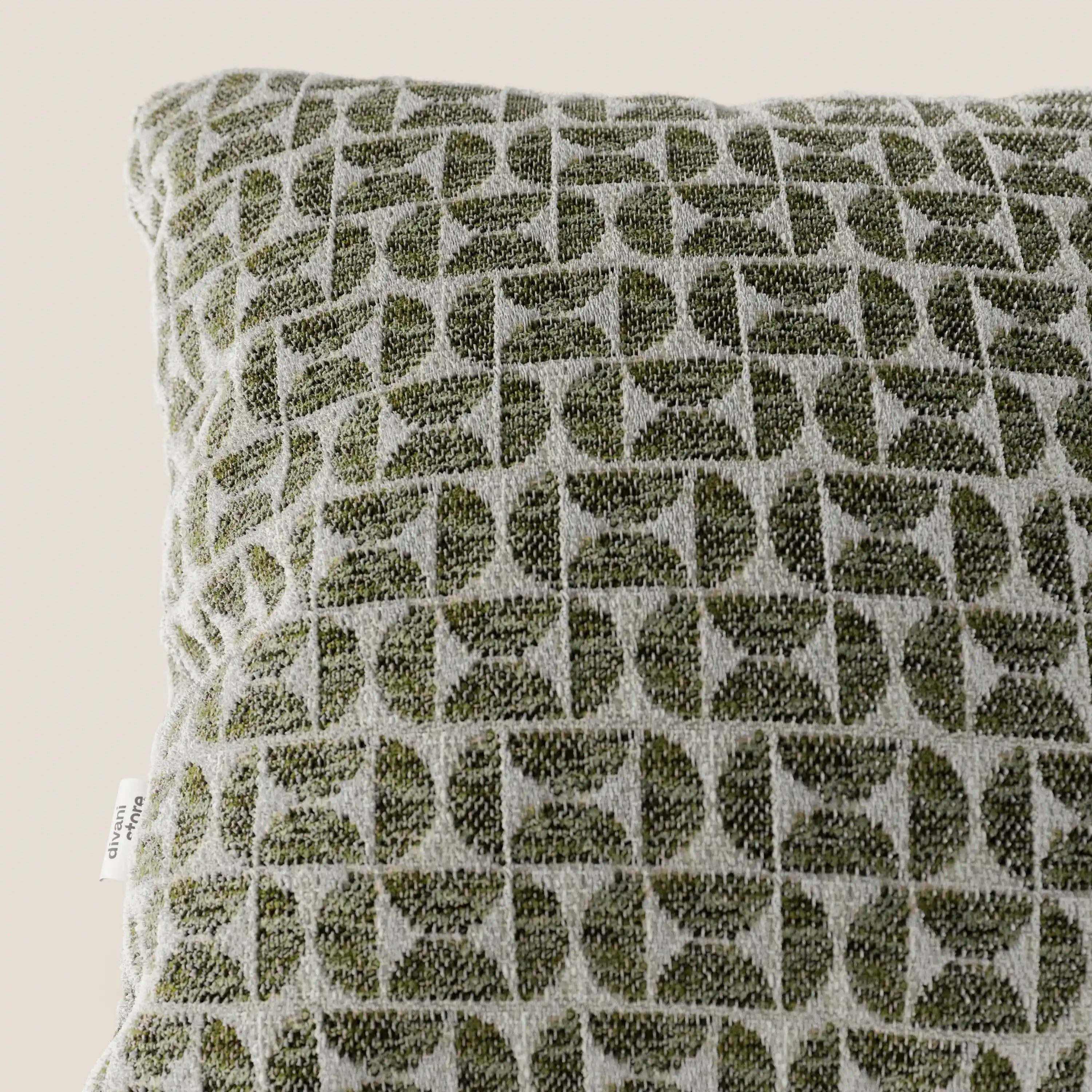 Un primo piano del cuscino decorativo Naxos Decoro 45x45 in lino di Divani.Store, che ne mette in risalto l'elegante motivo geometrico nei toni del verde oliva e del beige, caratterizzato da forme intrecciate. Sul bordo sinistro di questo cuscino decorativo è visibile una piccola etichetta bianca.