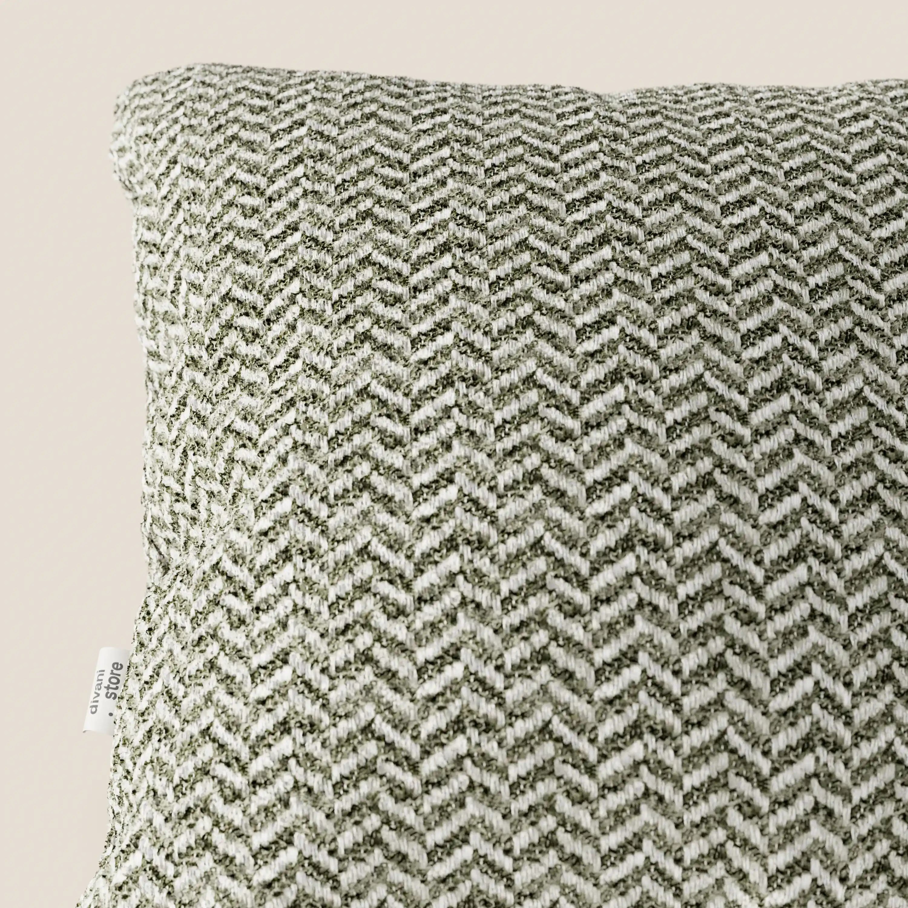 Primo piano del cuscino Sorrento 45x45 in lino di Divani.Store, che ne mette in risalto la trama a spina di pesce nei toni del verde oliva e del crema. Questo cuscino, lavabile in lavatrice, presenta una piccola etichetta laterale bianca su uno sfondo beige chiaro a tinta unita.
