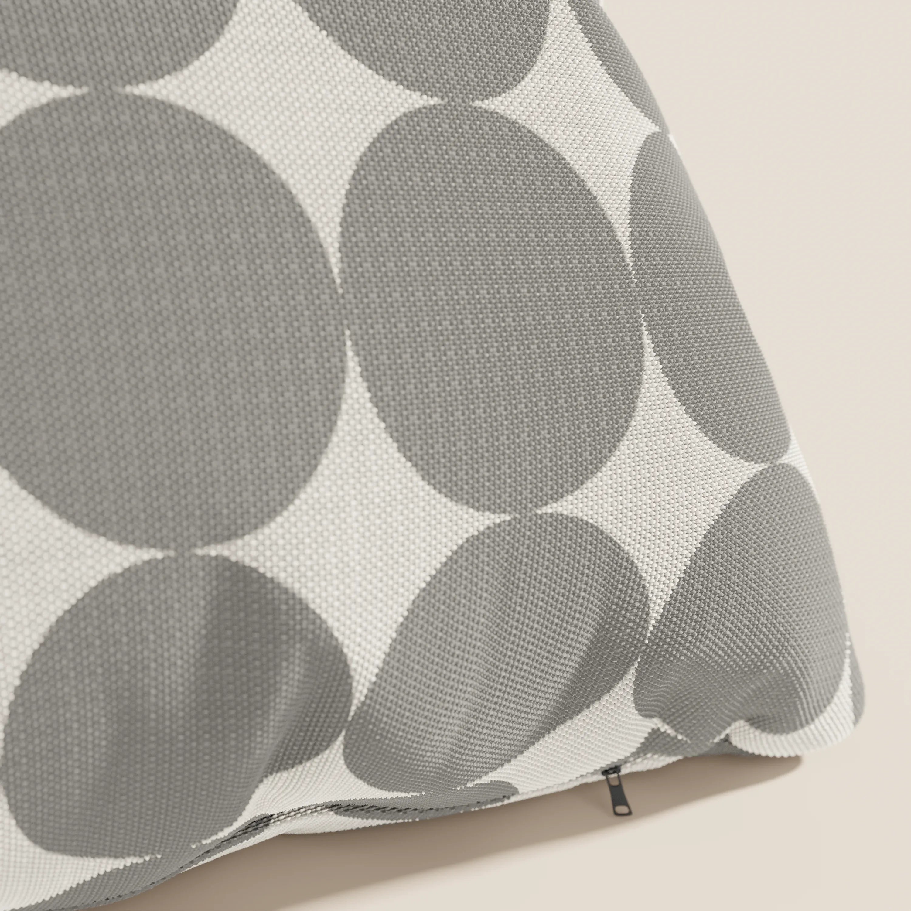 Primo piano dei "Dot cuscini geometrici" di Divani.Store, caratterizzati da un tessuto idrorepellente grigio con grandi cerchi grigi sovrapposti su bianco, mostrati inclinati per mostrare la cerniera del bordo inferiore su uno sfondo chiaro.