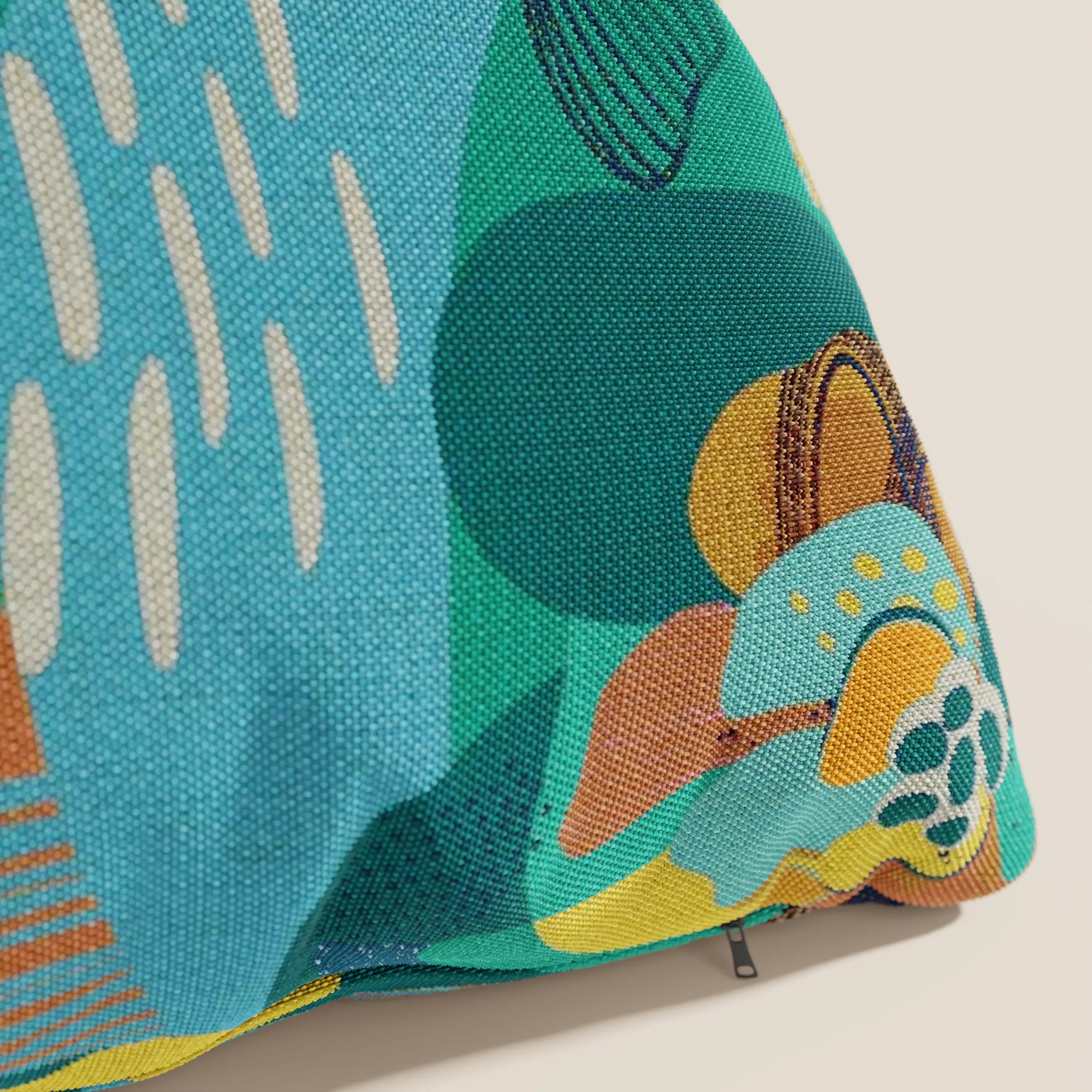 Primo piano del cuscino della collezione Joy di Divani.Store: un cuscino astratto multicolore in fresco tessuto di cotone verde acqua, resistente all'acqua, con fodera resistente e cerniera a vista sul bordo inferiore destro. Lavabile in lavatrice.