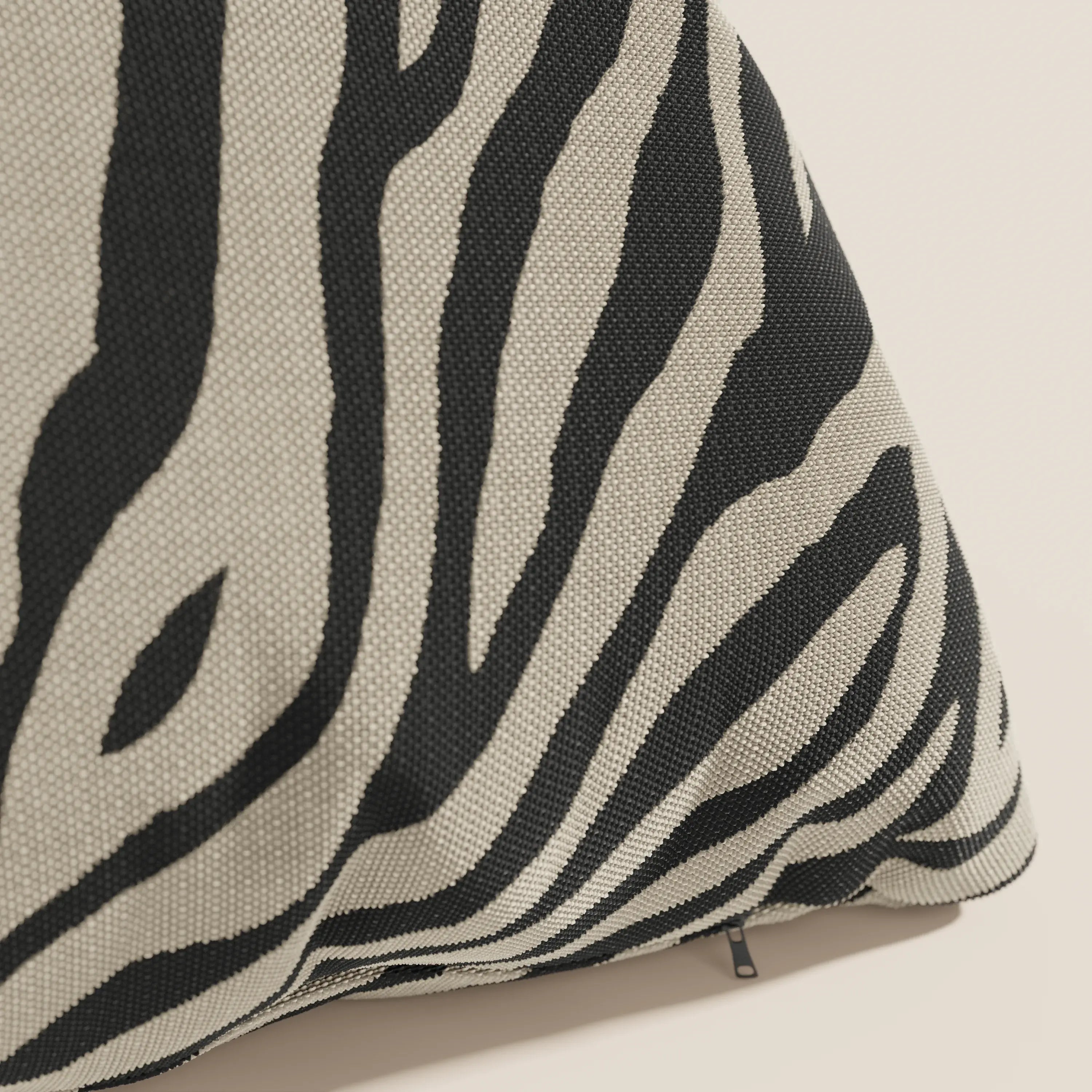 Primo piano di un cuscino Divani.Store Stripe geometrico in tessuto idrorepellente color tortora a righe zebrate nere e beige, che mostra la trama intrecciata e una piccola chiusura lampo nera su uno sfondo chiaro.