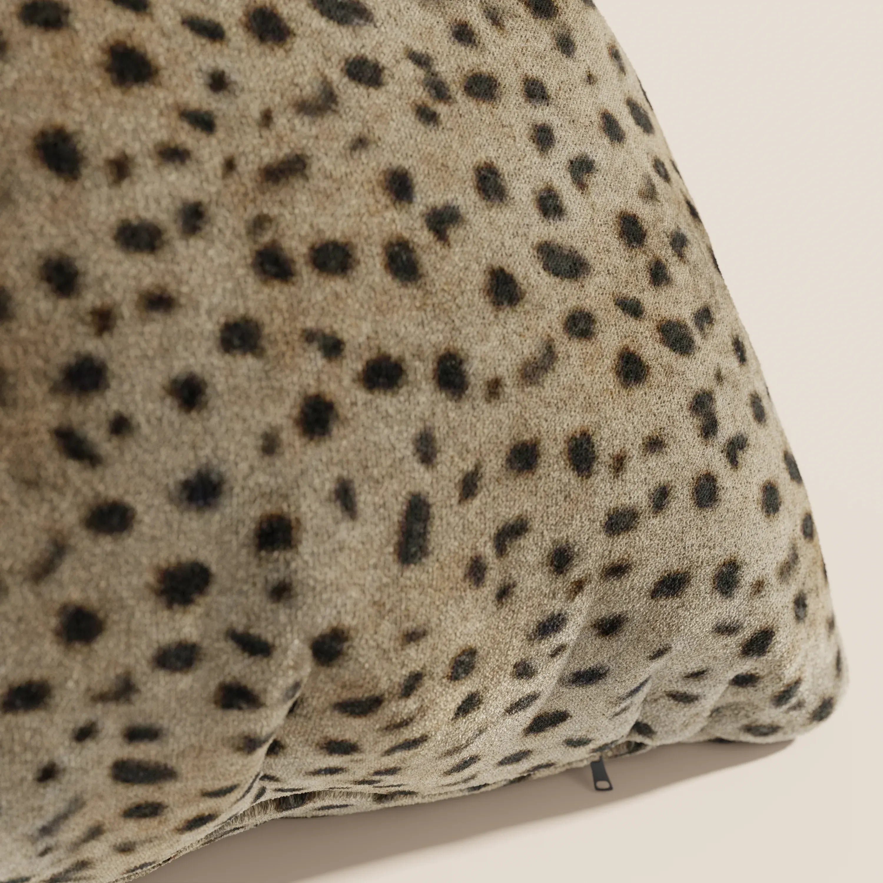 Primo piano del cuscino Wild della collezione Wild di Divani.Store, caratterizzato da un motivo leopardato su microfibra impermeabile color tan. Il cuscino 45x45 in peluche presenta bordi curvi e un decoro elegante ispirato alla pelliccia animale.