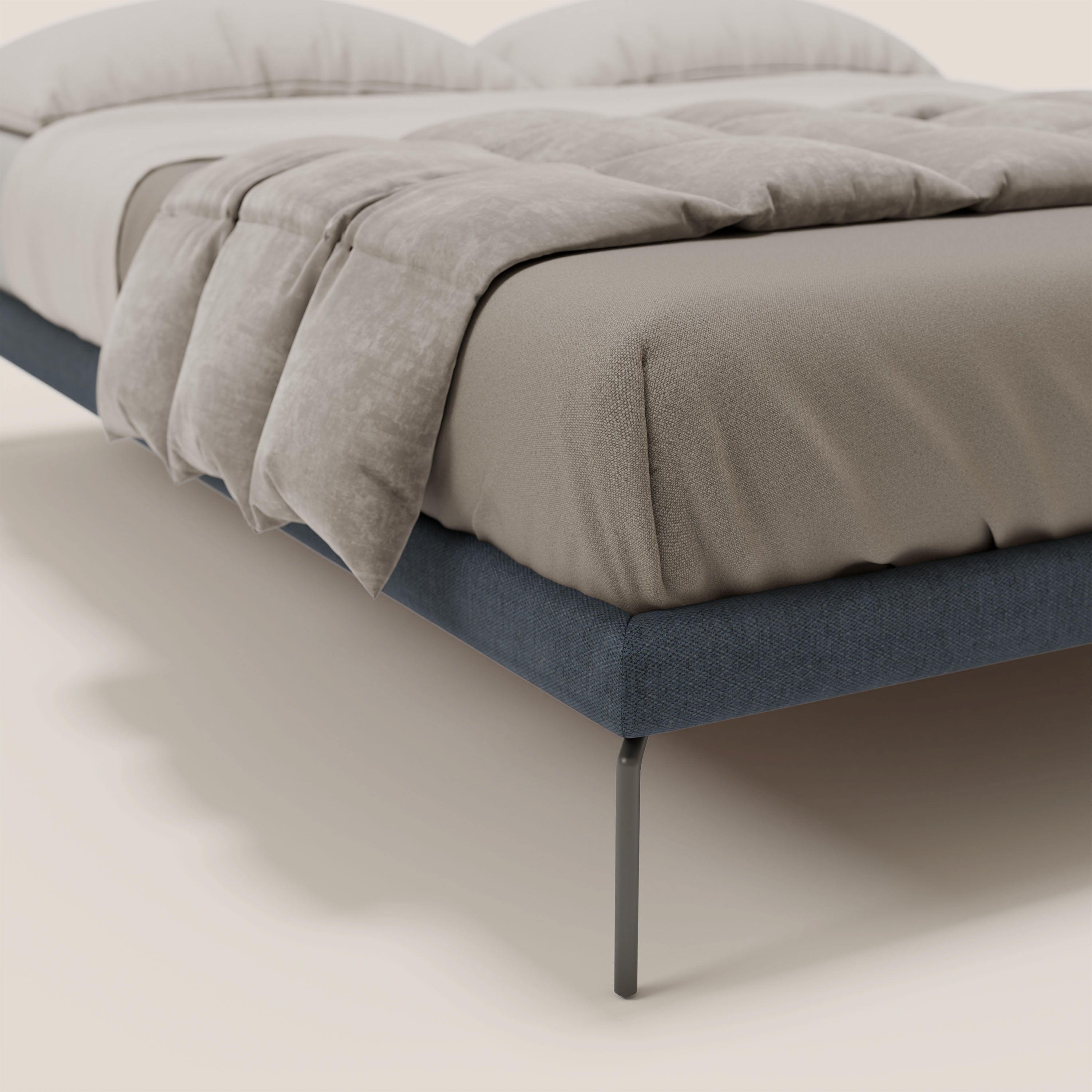Primo piano del sommier sfoderabile Letti.store Ring con gambe nere alte 24 cm, rivestito in tessuto impermeabile T14 blu, confezionato con biancheria beige e inserito in uno sfondo chiaro.