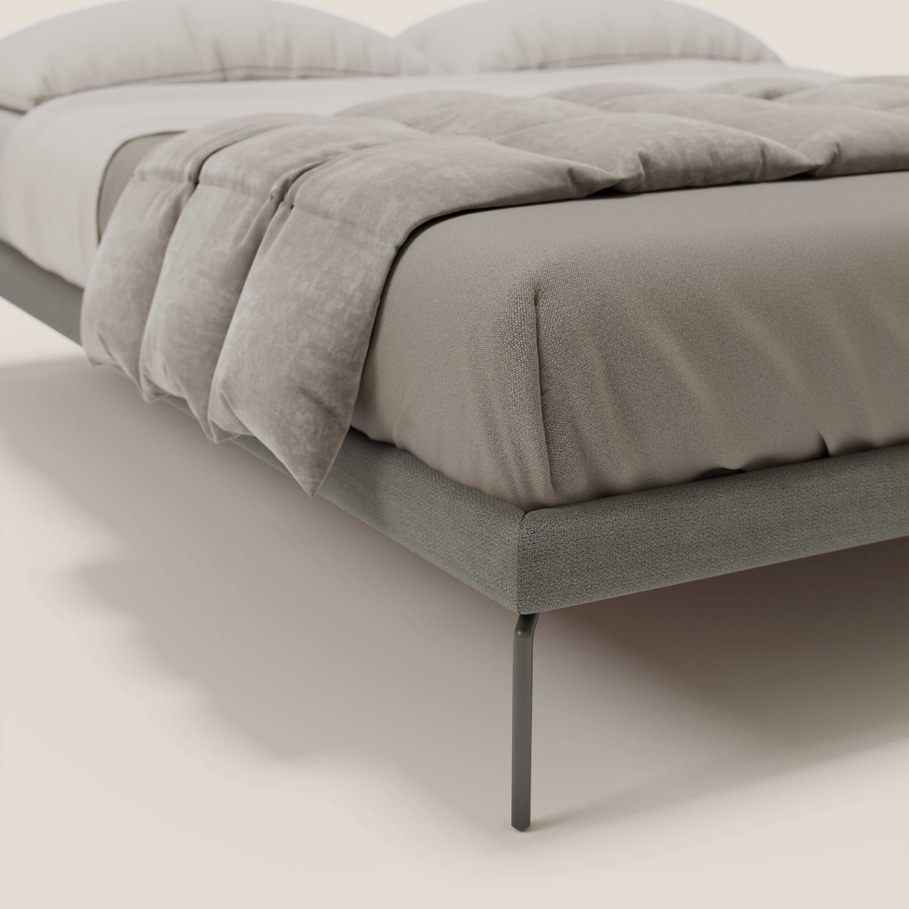 Un primo piano del sommier sfoderabile Ring di Letti.store con gambe alte 24 cm, rivestito in tessuto impermeabile grigio T14, abbinato a biancheria da letto color tortora. Il design moderno risalta sullo sfondo beige, concentrandosi sull'angolo inferiore del letto.