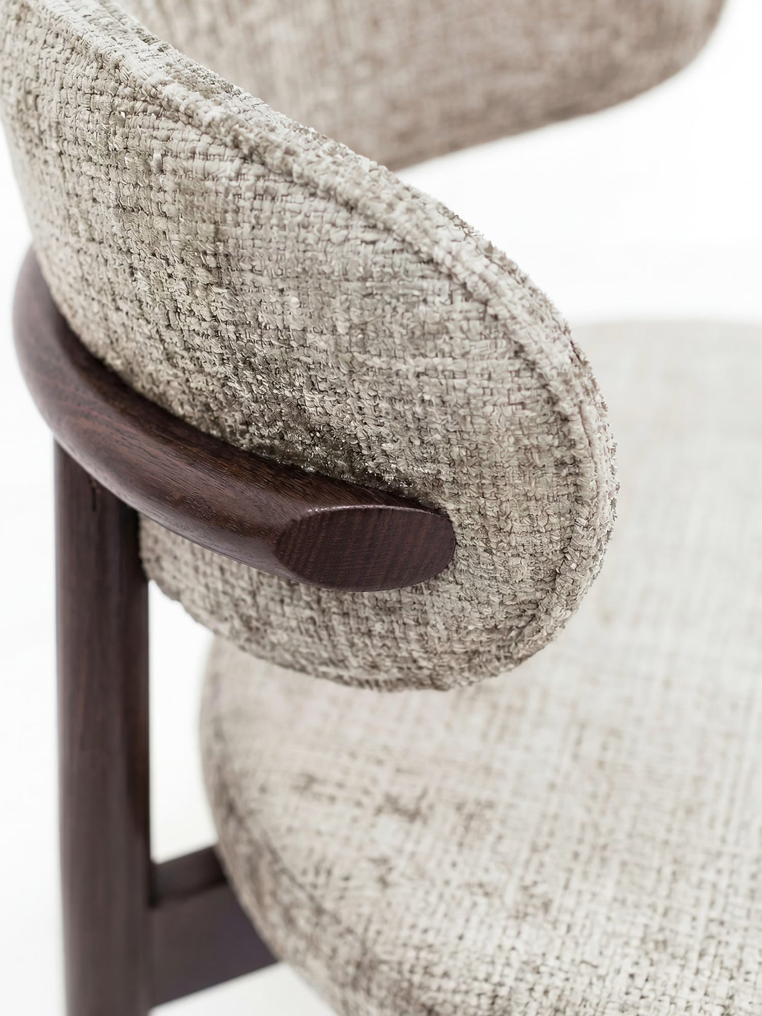 Primo piano della sedia imbottita Dafne di Divani.Store, caratterizzata da un rivestimento in ciniglia certificato OEKO-TEX® color beige e da una struttura curva in legno massello di wengé, che creano un contrasto sofisticato per un look contemporaneo e raffinato.